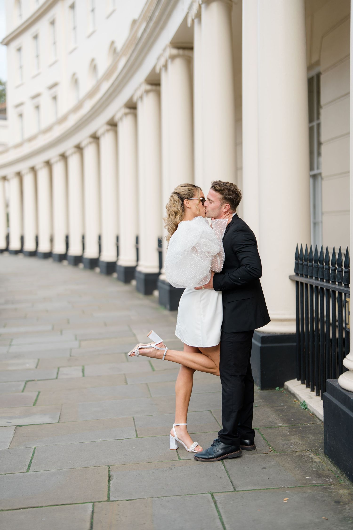 Romantic sequence captured under classic London architecture with white columns.