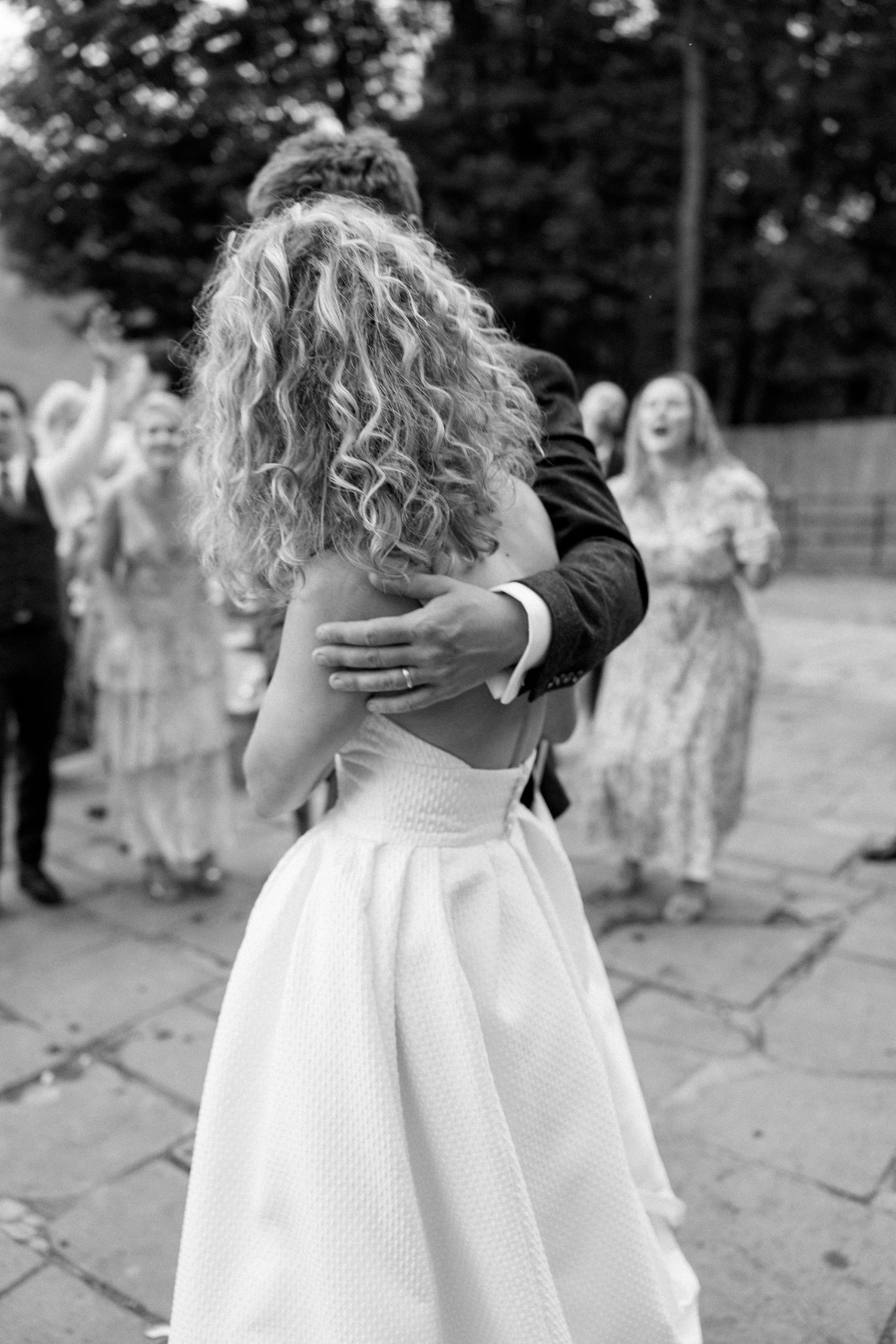 Black and white photo of an intimate dance moment at a wedding reception with guests in background.