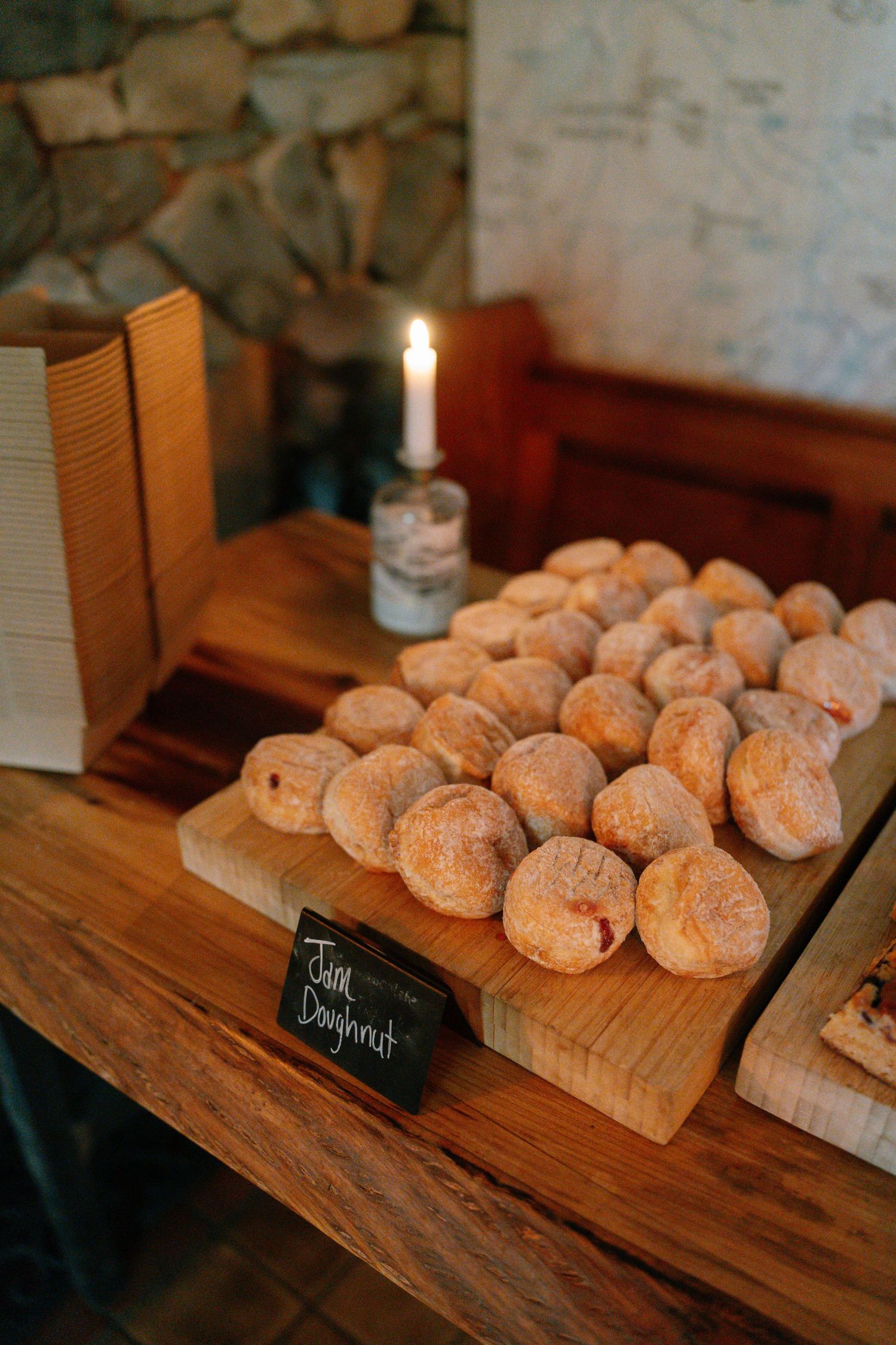 Freshly baked doughnuts displayed on wooden boards with a small chalkboard sign.