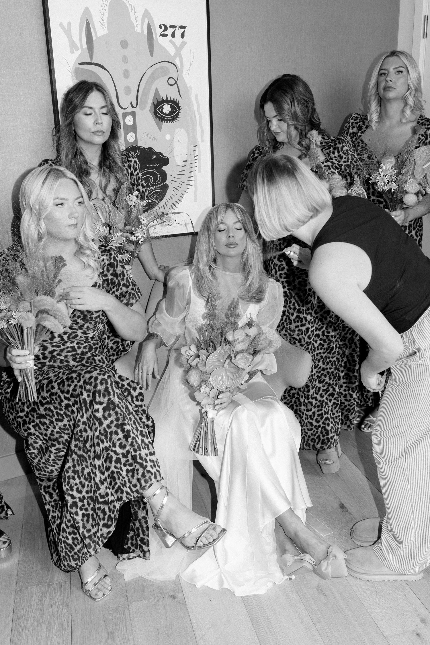 Wedding party in leopard print dresses gathered around bride holding bouquets.