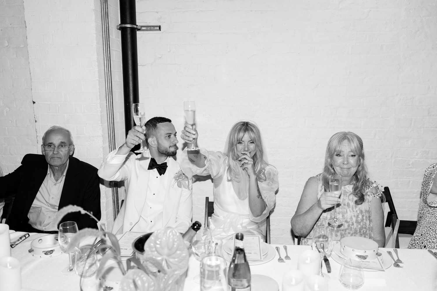 Wedding reception guests celebrate and toast at dining tables.