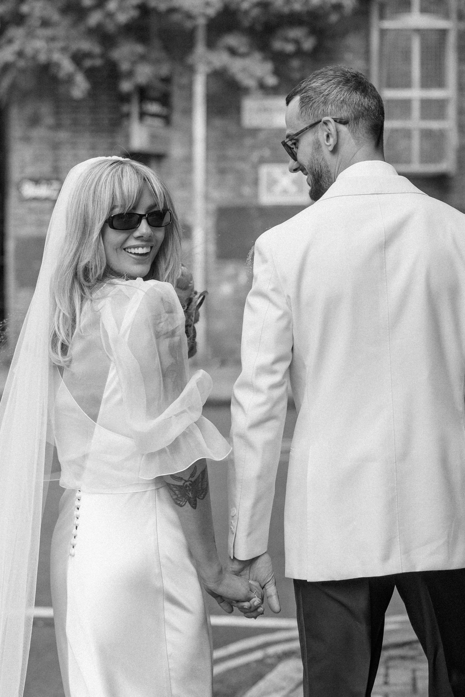 Elegant couple in white formal wear walking together outdoors.
