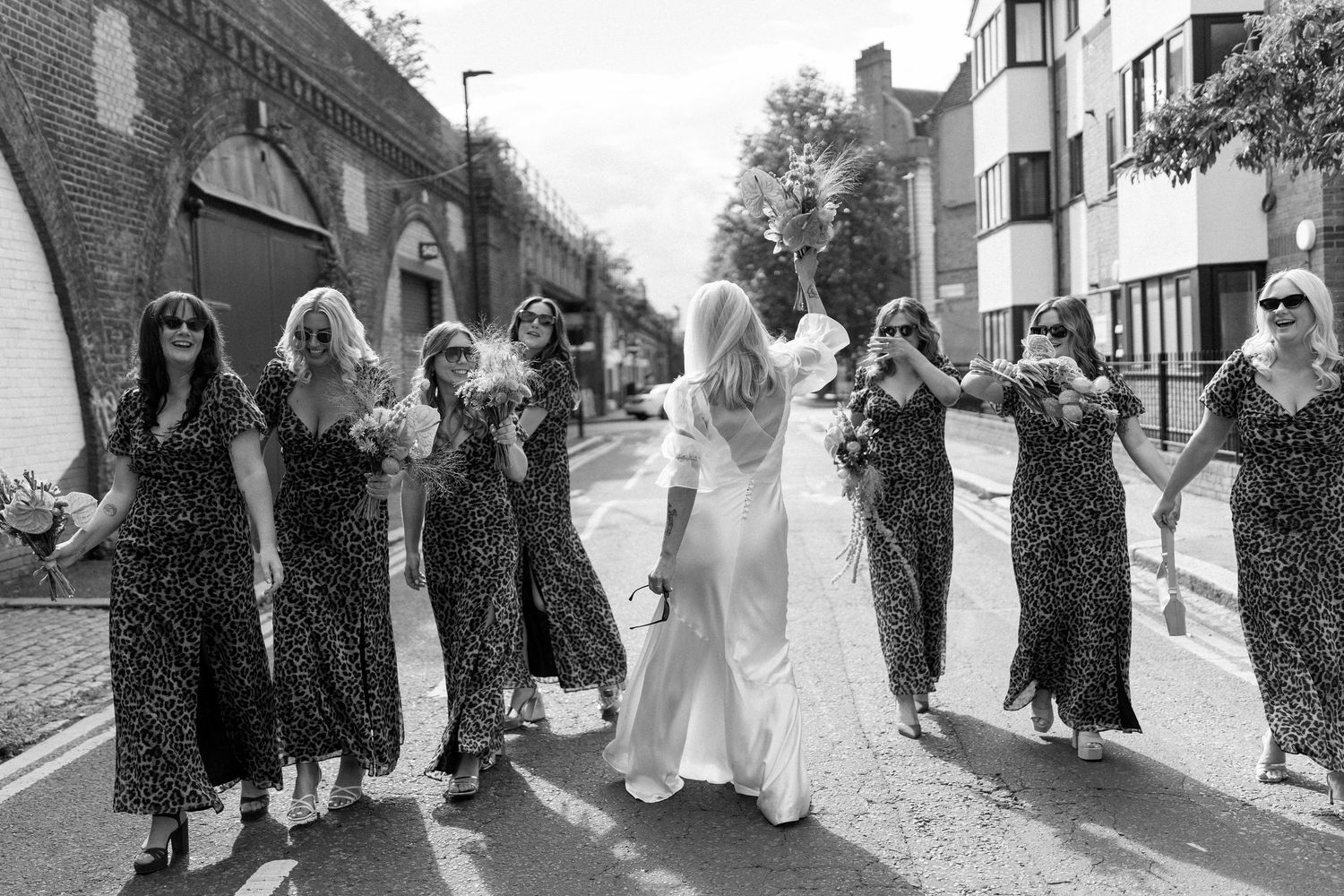 Wedding party and guests walking together along a stone path in formal attire.