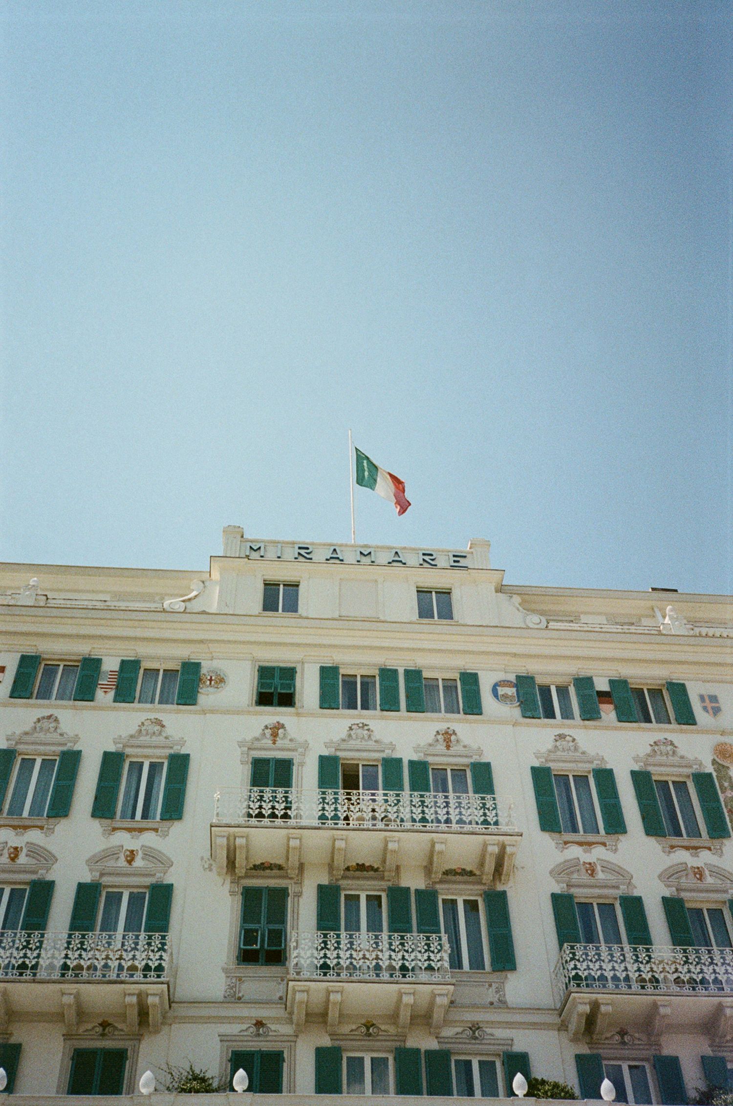 Grand Hotel Miramare facade with green shutters and Italian flag in Santa Margherita Ligure, Italy.
