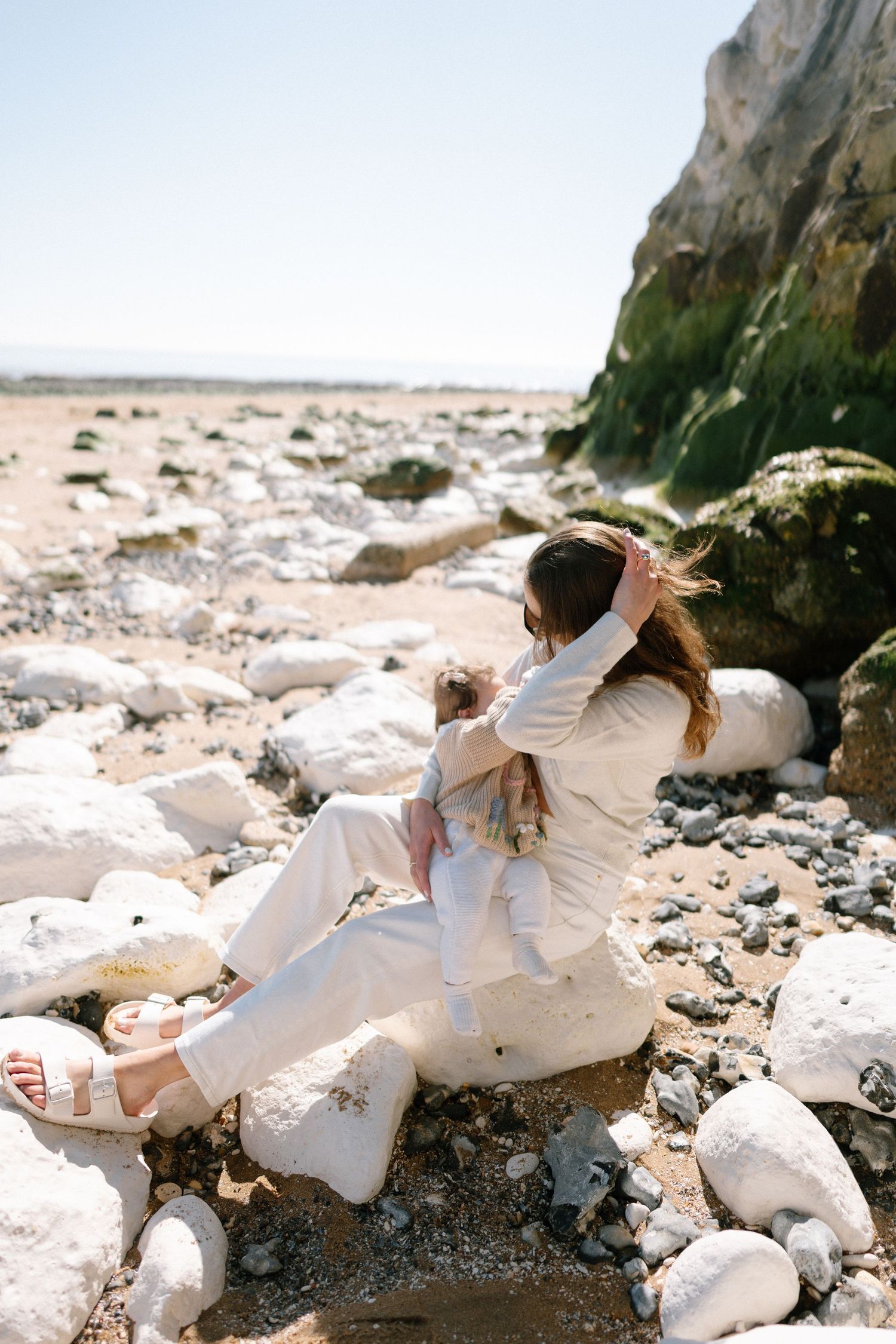Artistic photo series of people in white clothing posing against dramatic coastal cliffs.