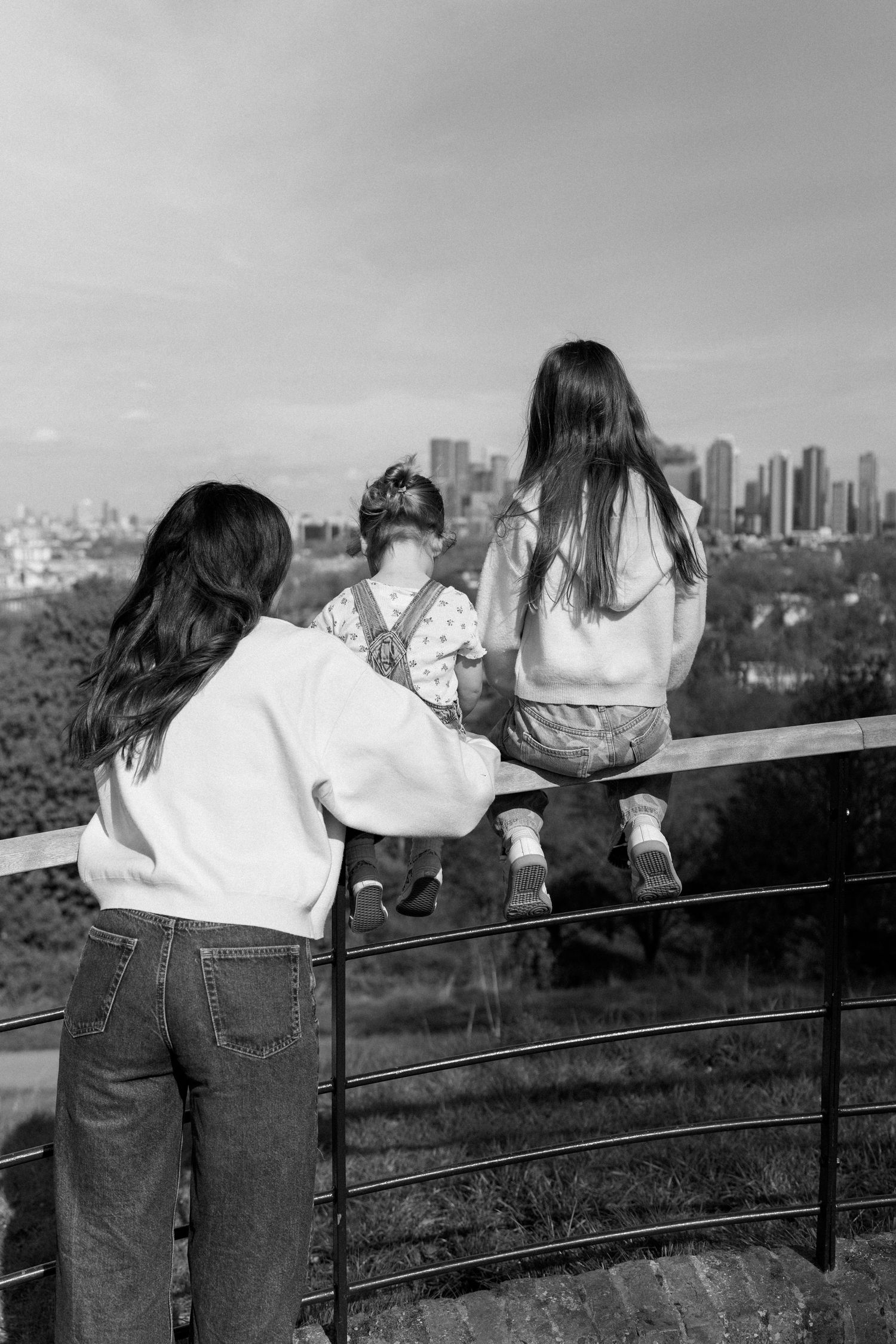 People leaning on a railing overlooking a cityscape with tall buildings in the distance.