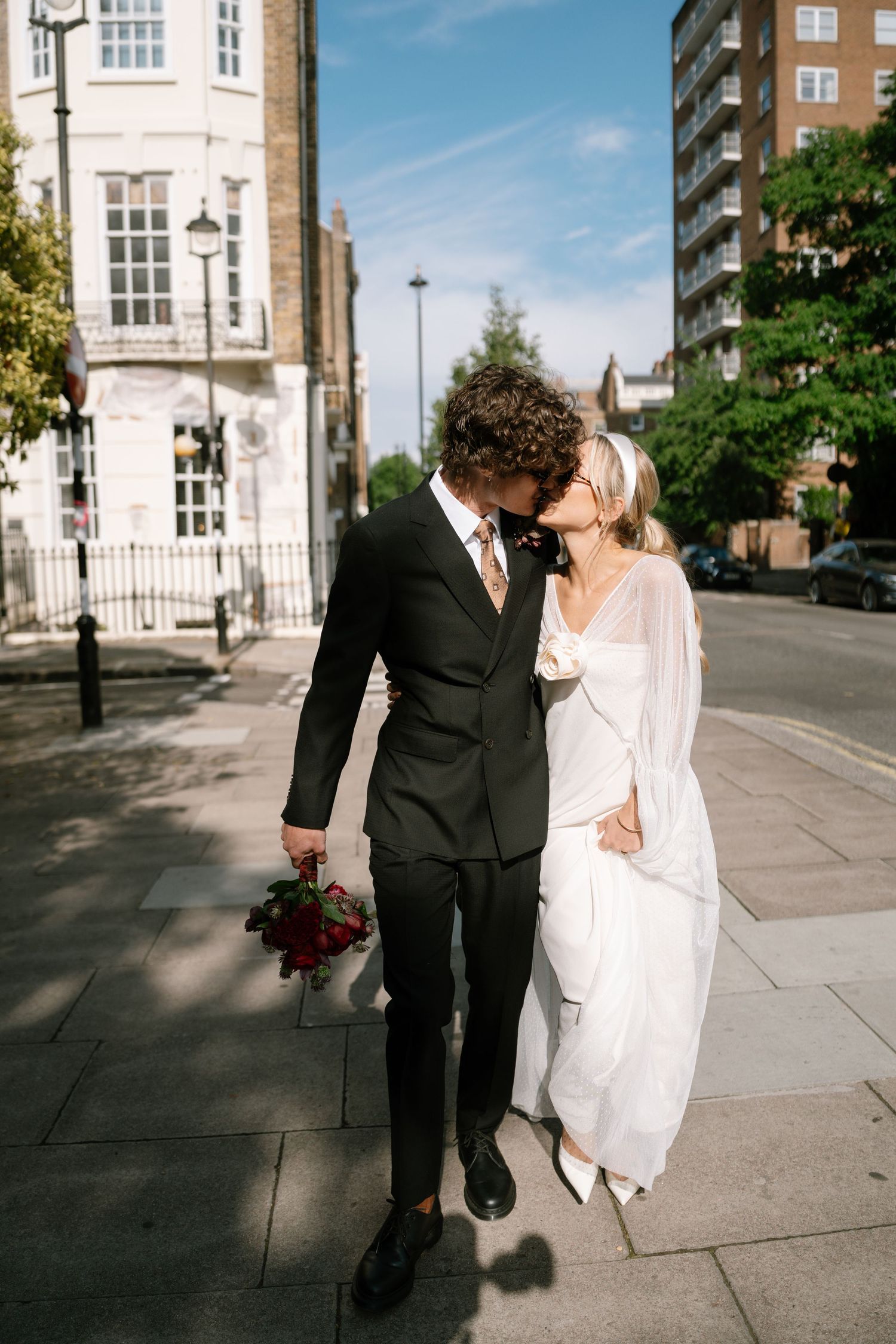 Wedding couple sharing an intimate moment on a bright city street.