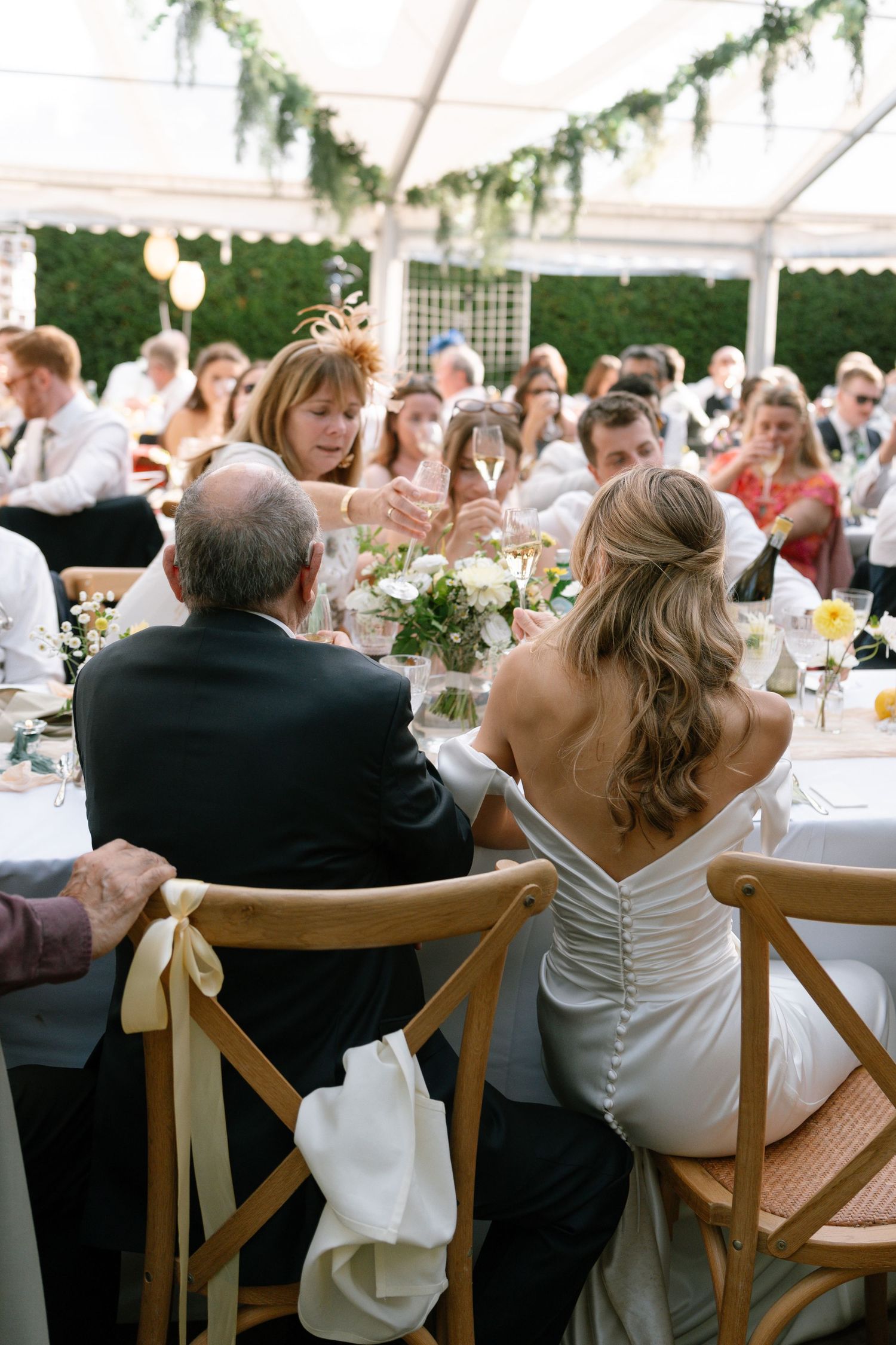 Wedding reception guests seated at decorated tables under a white tent.