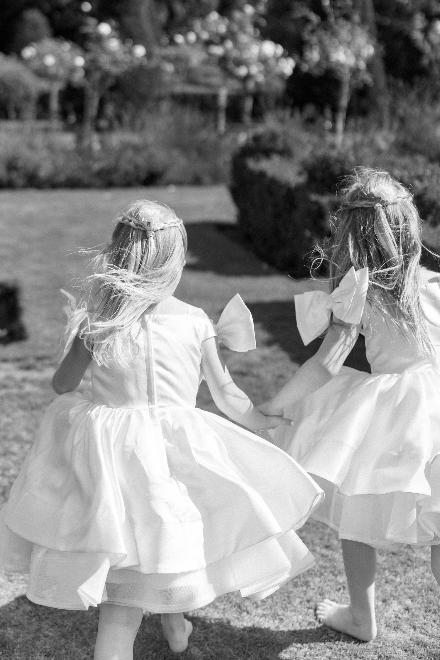 Black and white photo of children in flowing white dresses dancing in a garden.