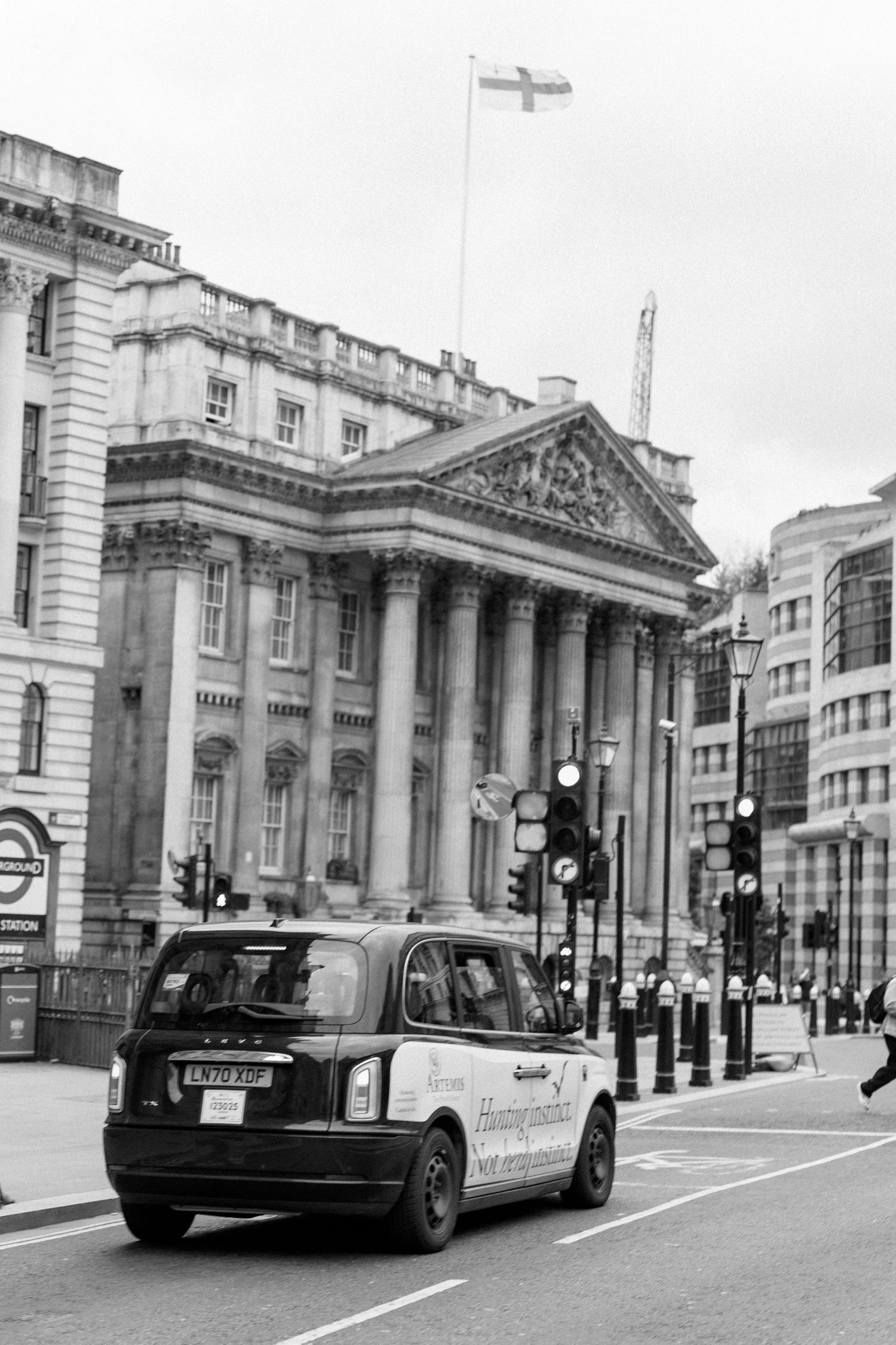 Black and white street scene of London with classic taxi and historic architecture.