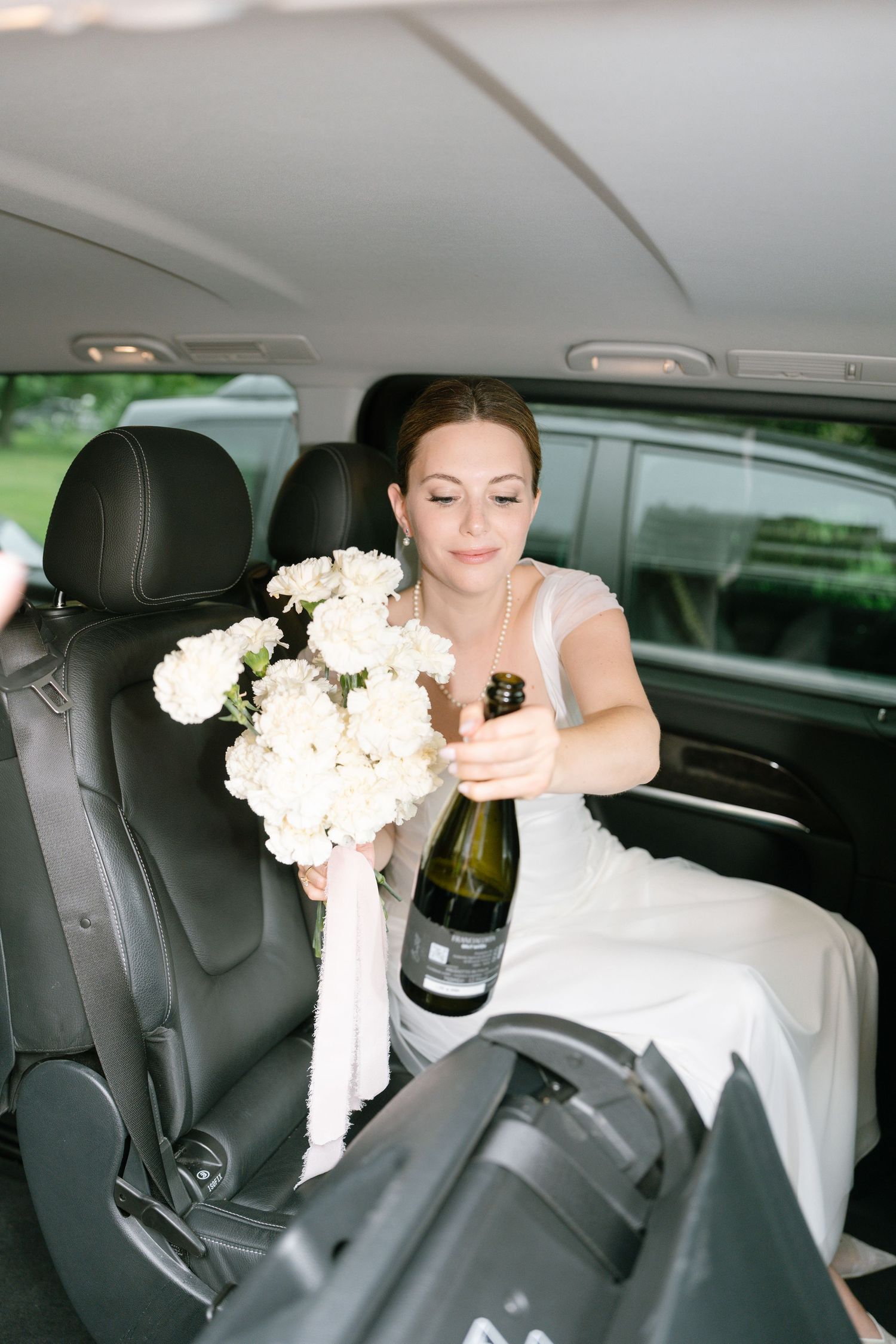 Black and white sequence of someone in a wedding dress laughing while seated in a vehicle.
