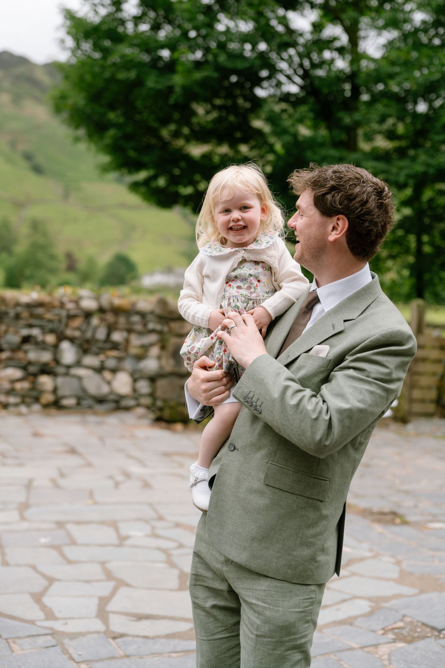 Joyful wedding moment captured in an outdoor garden setting with stone walls and greenery.