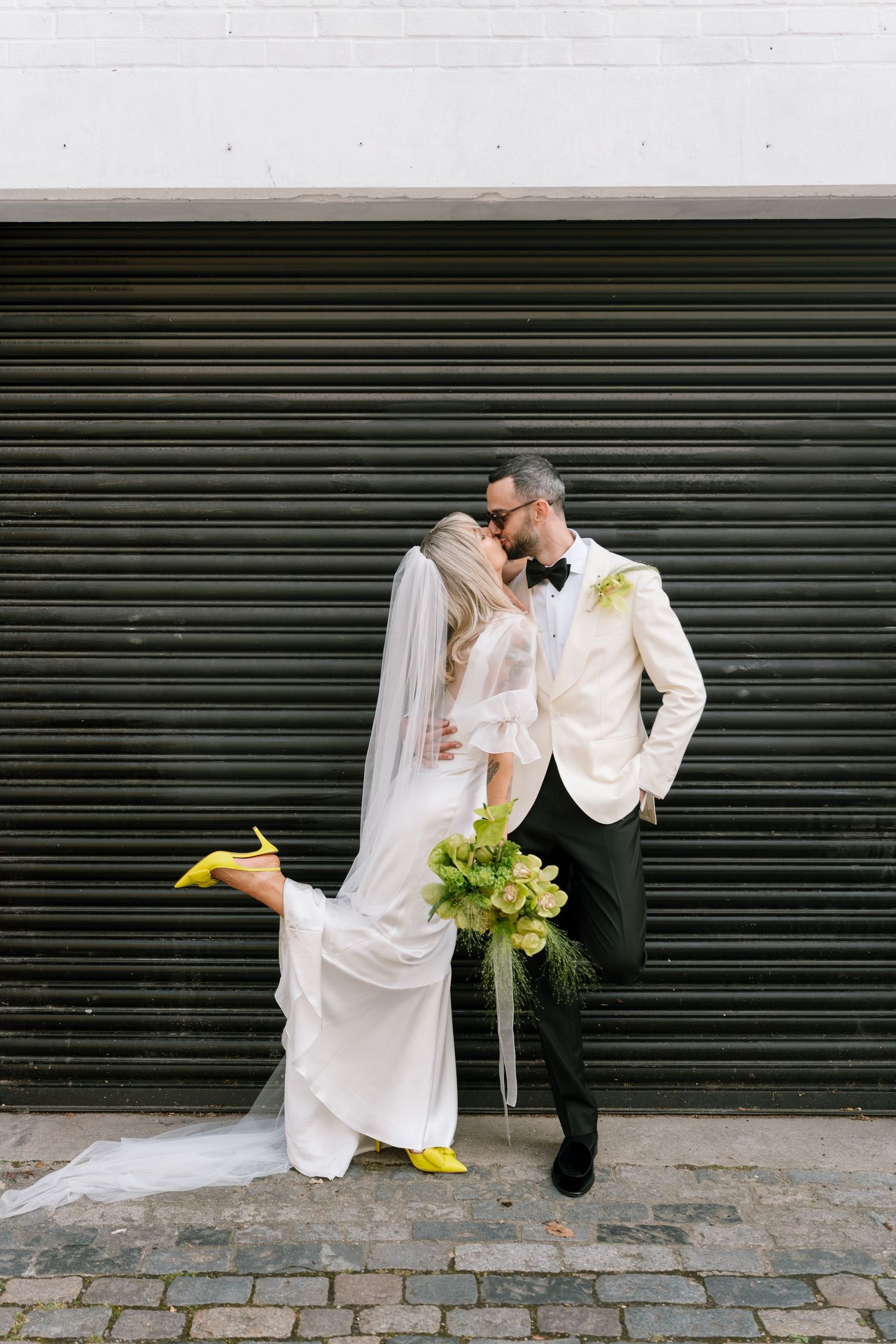 Wedding couple embraces against industrial backdrop with rolling metal door.