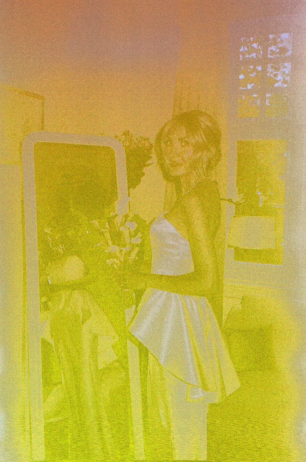 Woman in white strapless dress posing by mirror, captured in vintage yellow-toned film photography style.
