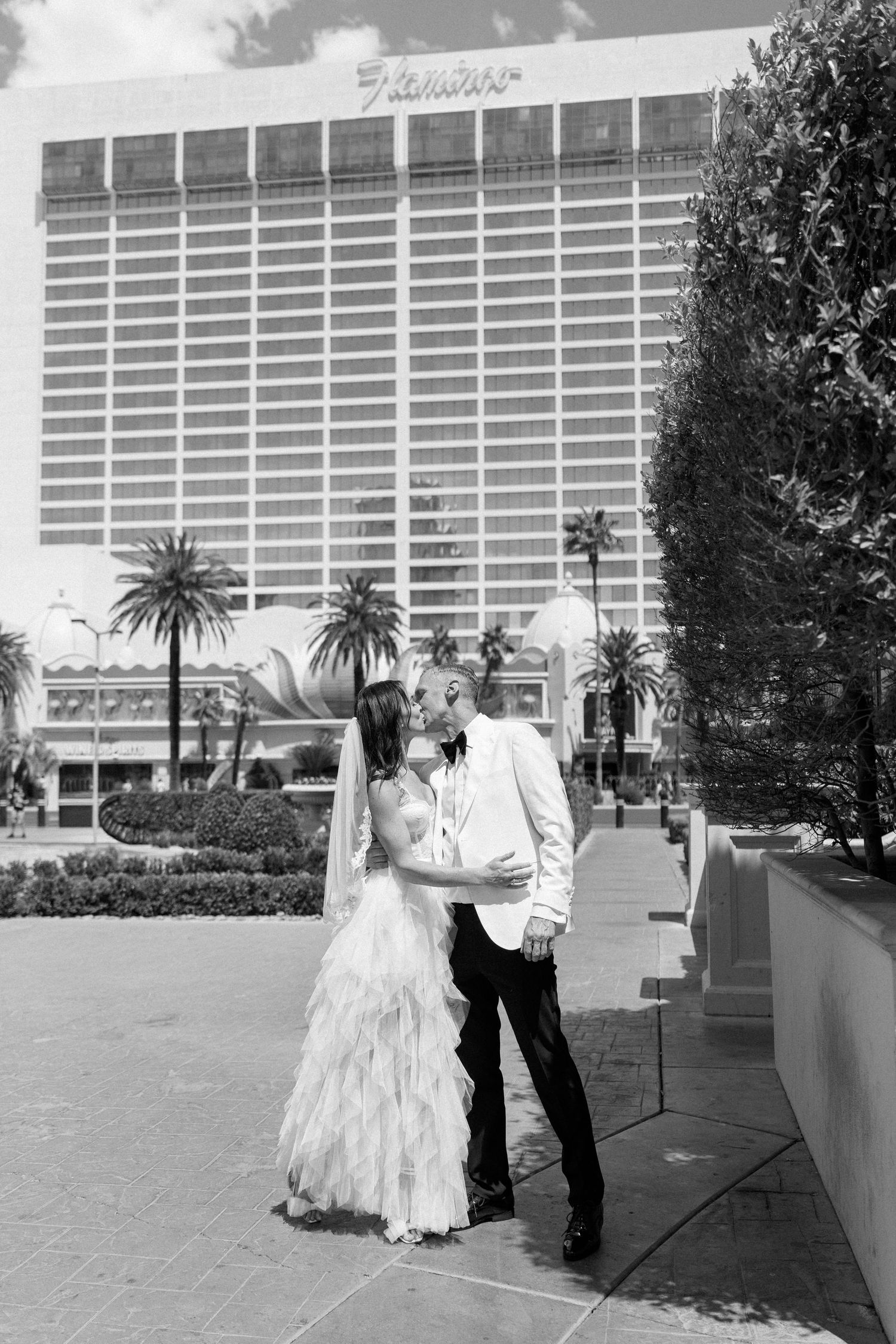 A black and white wedding portrait in front of the Flamingo Las Vegas hotel.