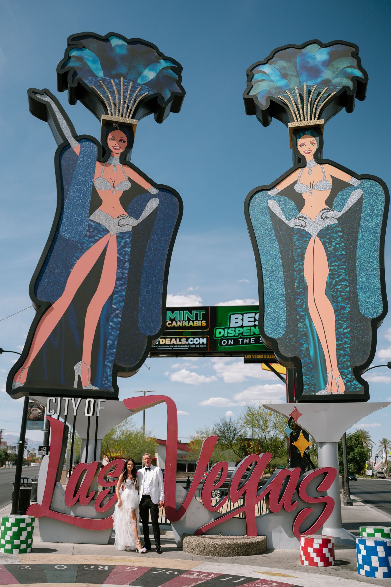 Vintage-style neon signs featuring retro pin-up girl silhouettes against a blue sky.