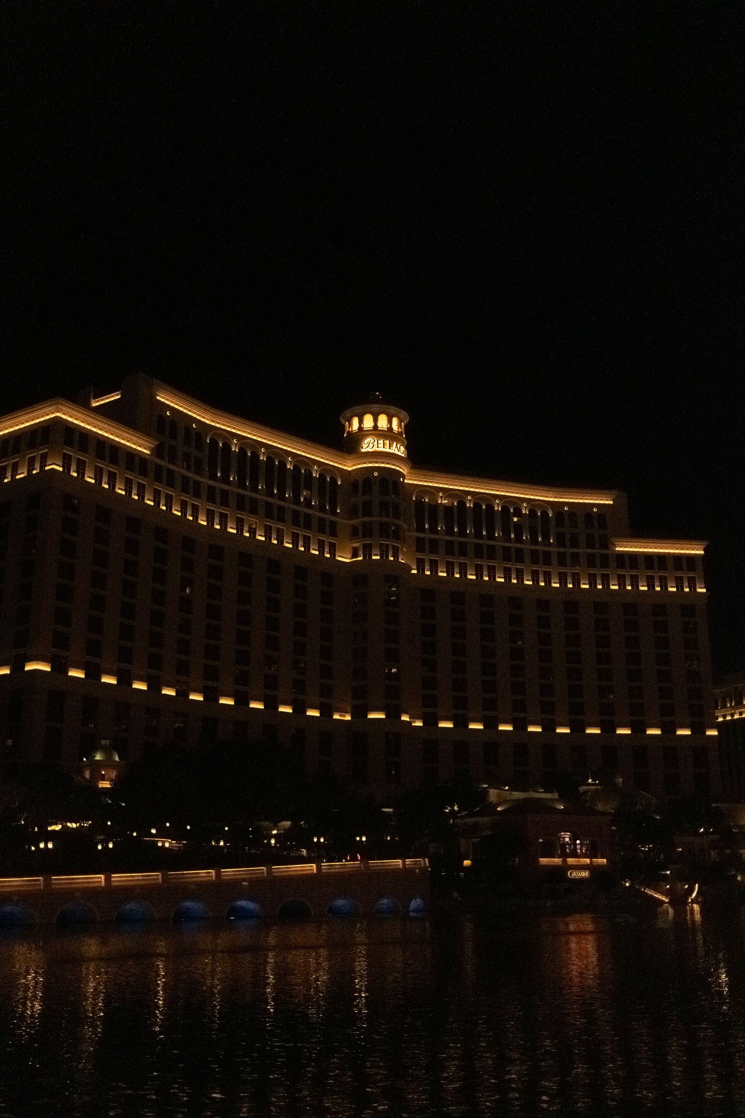 The Bellagio hotel illuminated at night with its reflection in the fountain water.