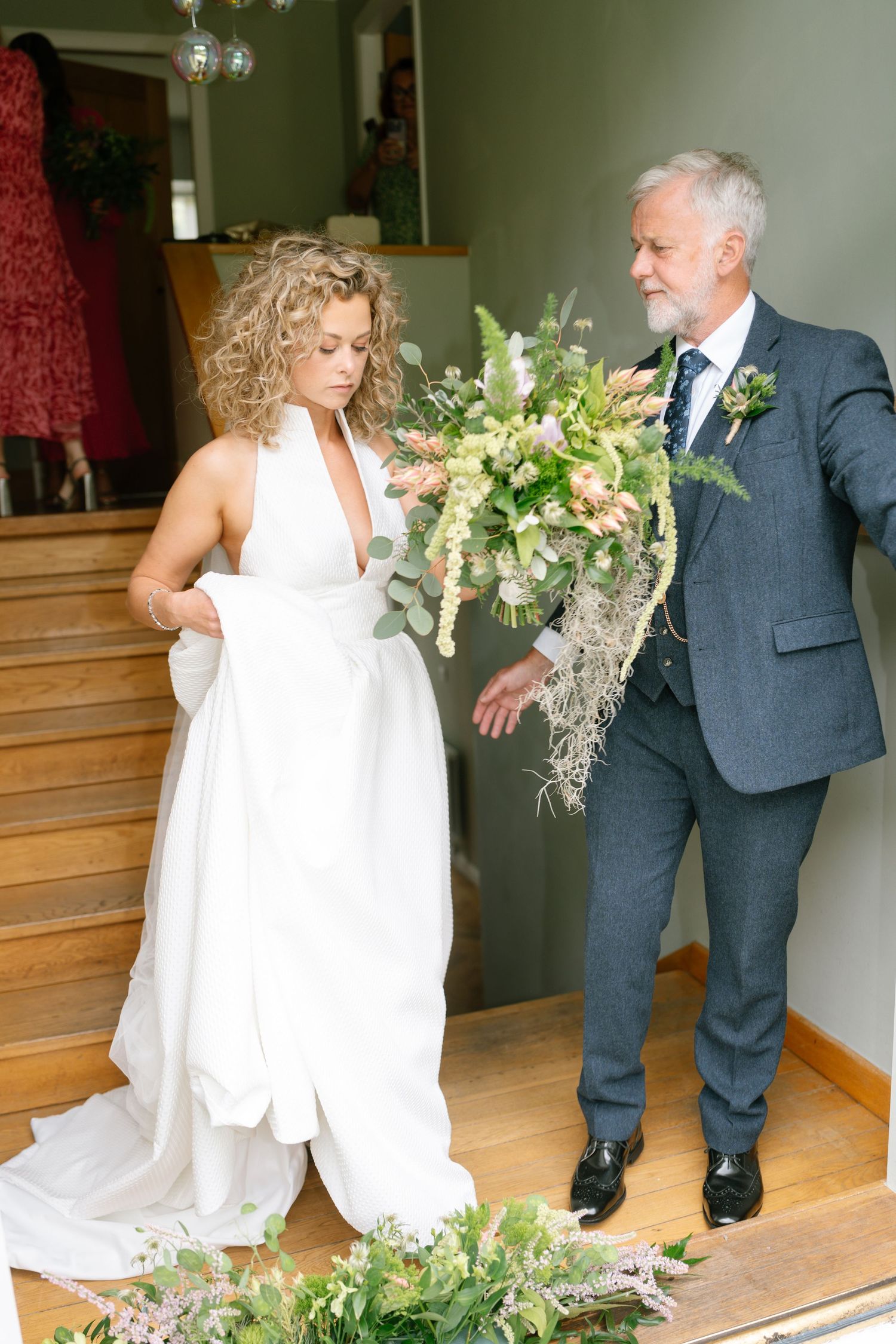 An intimate wedding moment on wooden stairs with elegant floral arrangements.
