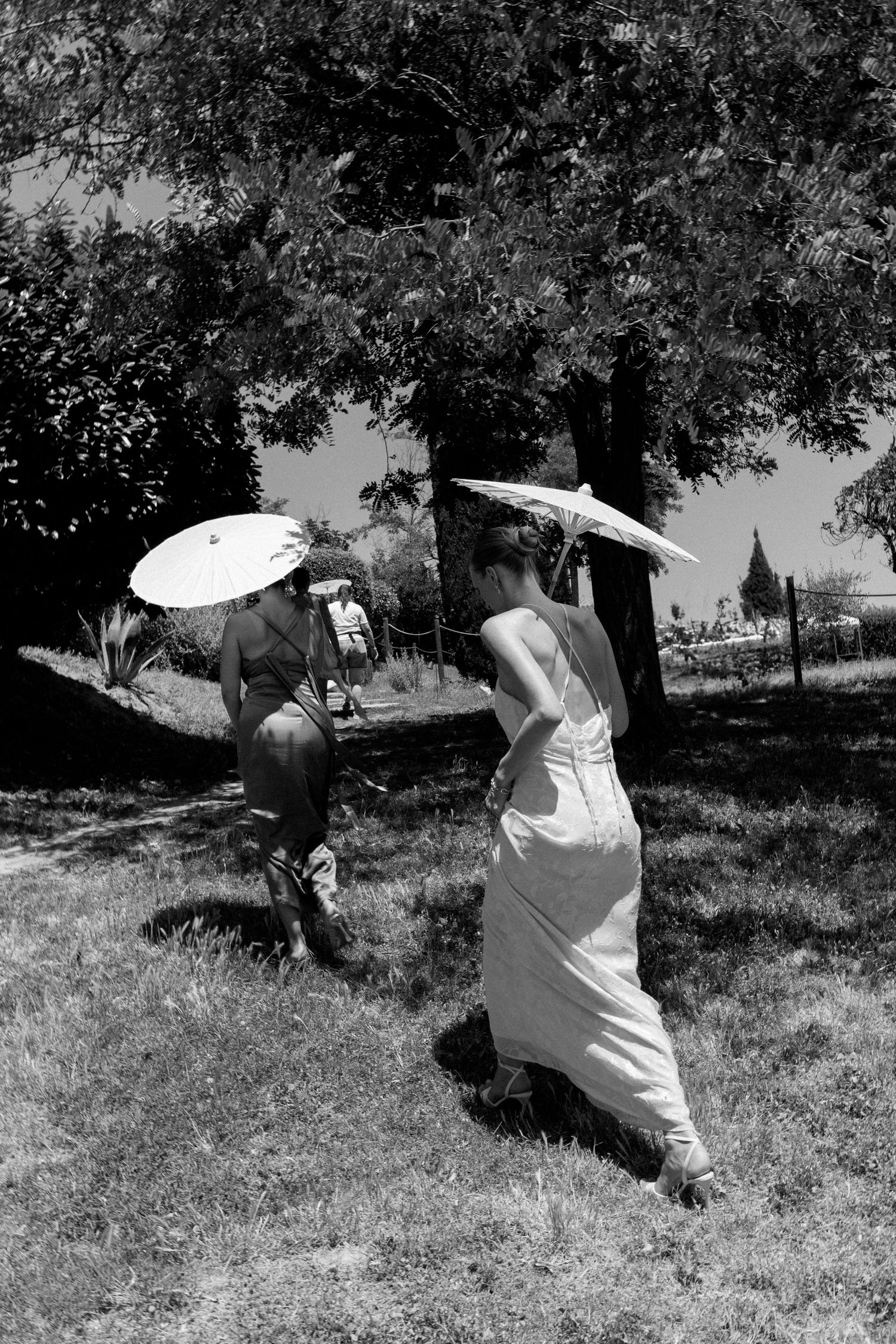 Black and white sequence of figures moving through a grassy field with parasols.