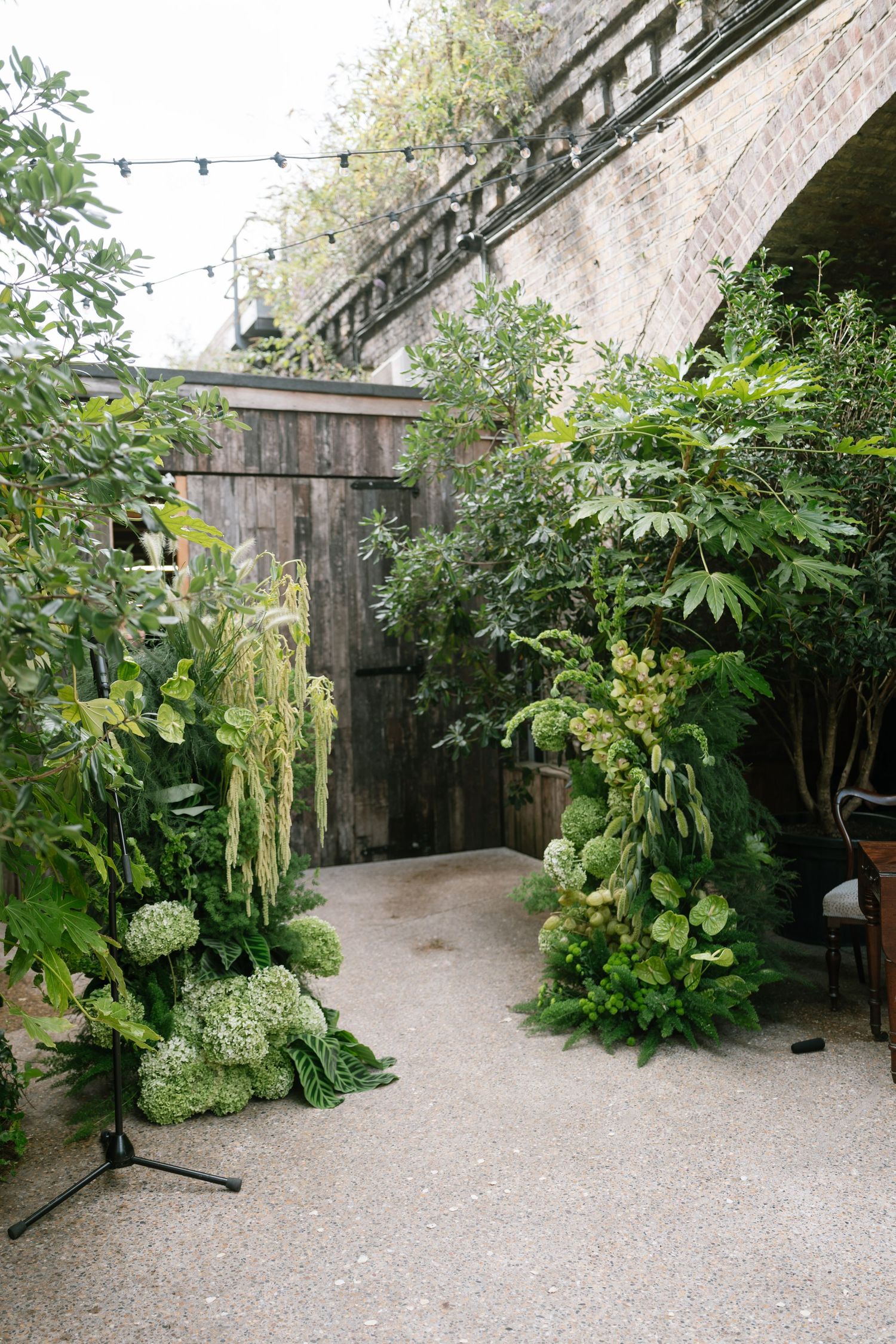 Lush garden pathway with greenery and stone walls creates an enchanting outdoor venue setting.