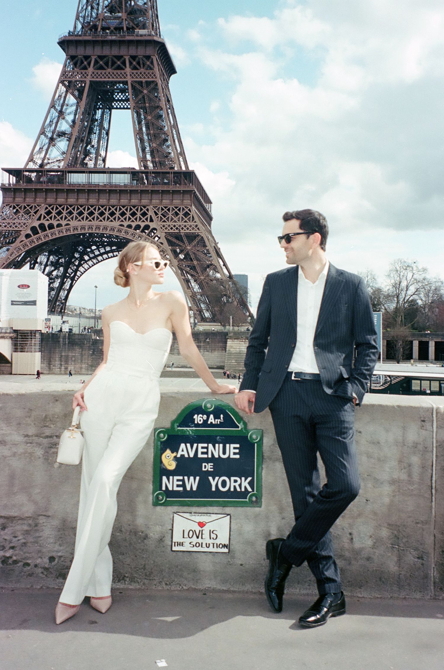 Romantic couple poses in formal attire near the Eiffel Tower with New York Avenue street sign in Paris.