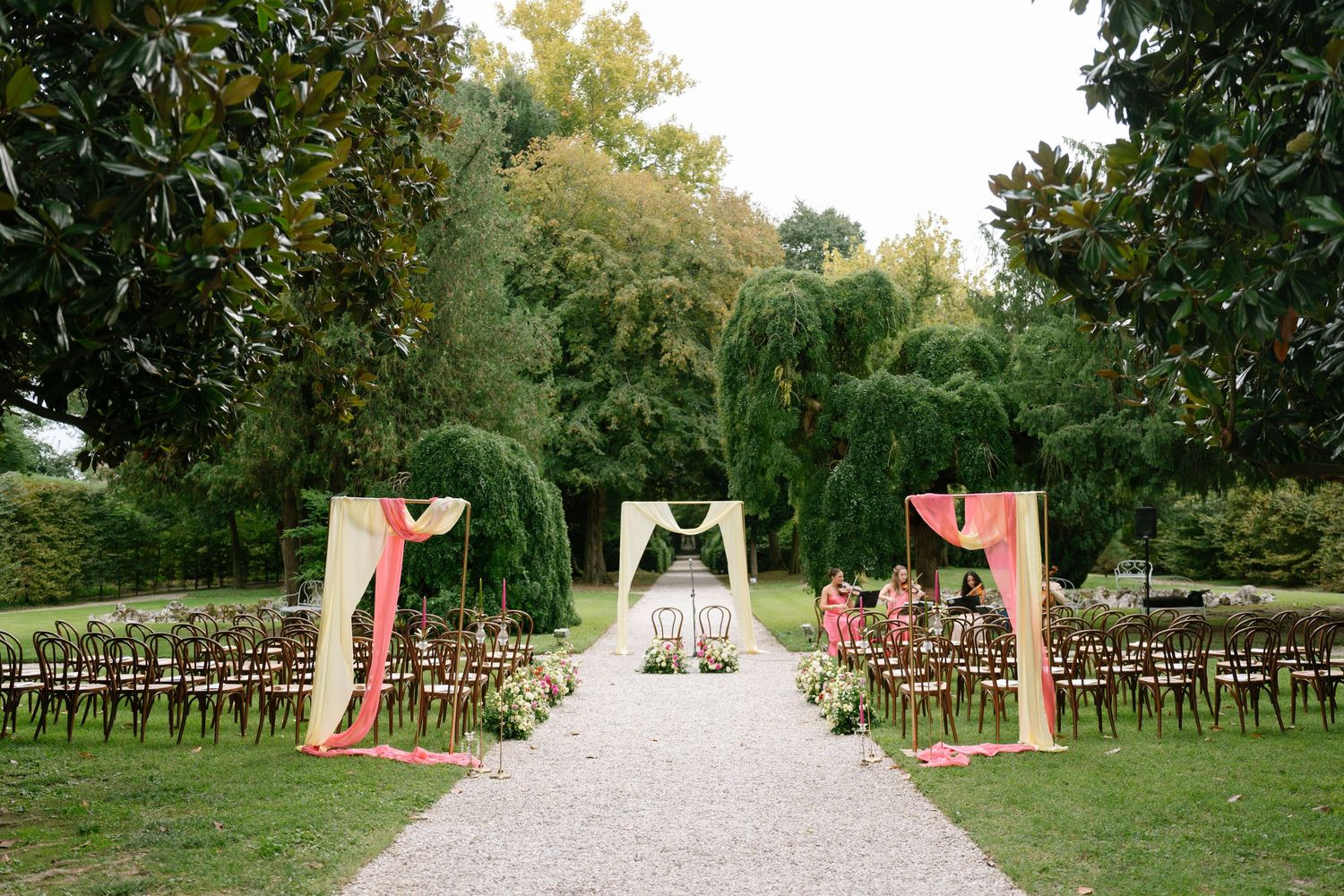 Outdoor wedding ceremony setup with wooden chairs along a stone pathway.