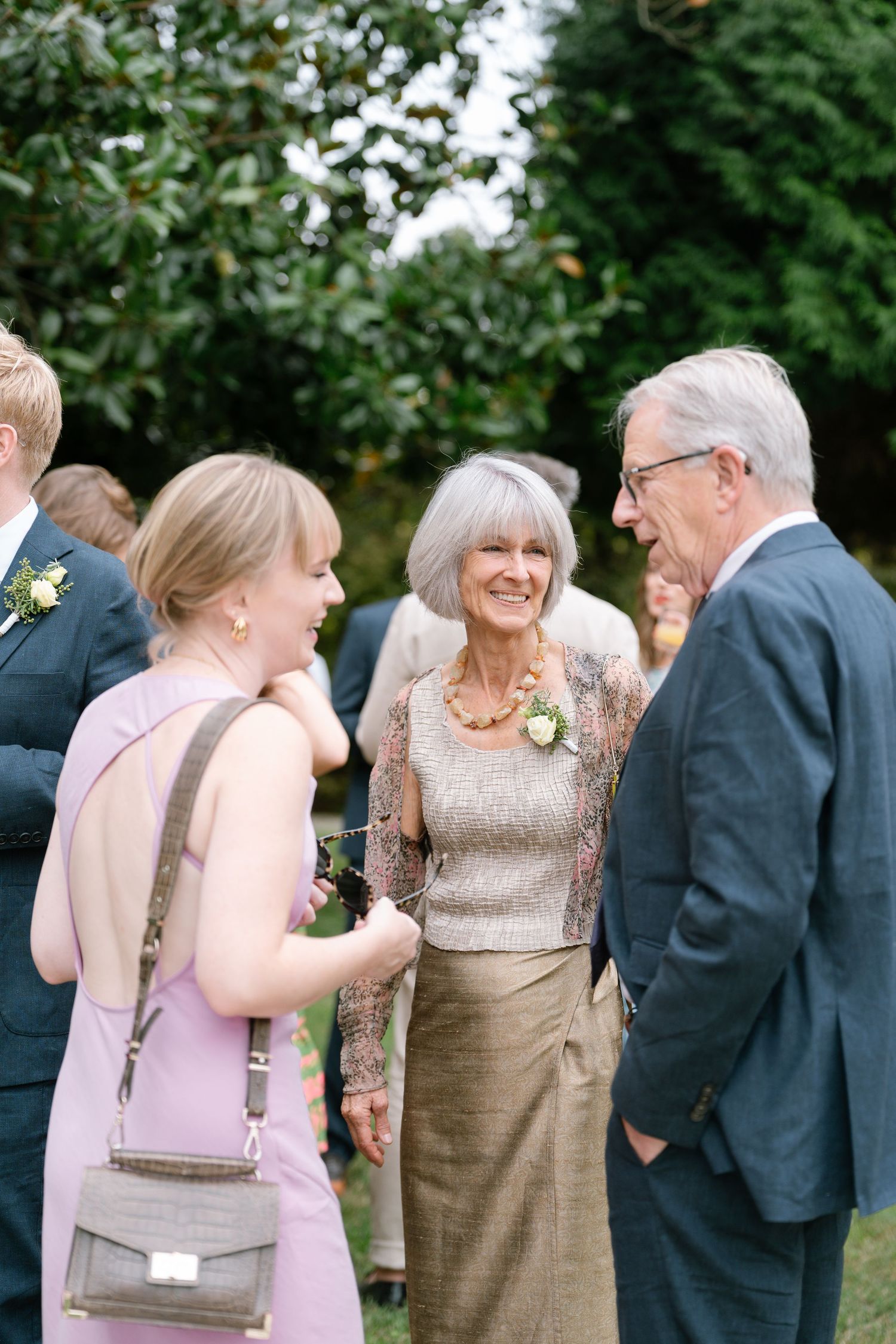 Wedding guests share joyful laughter during an outdoor celebration.