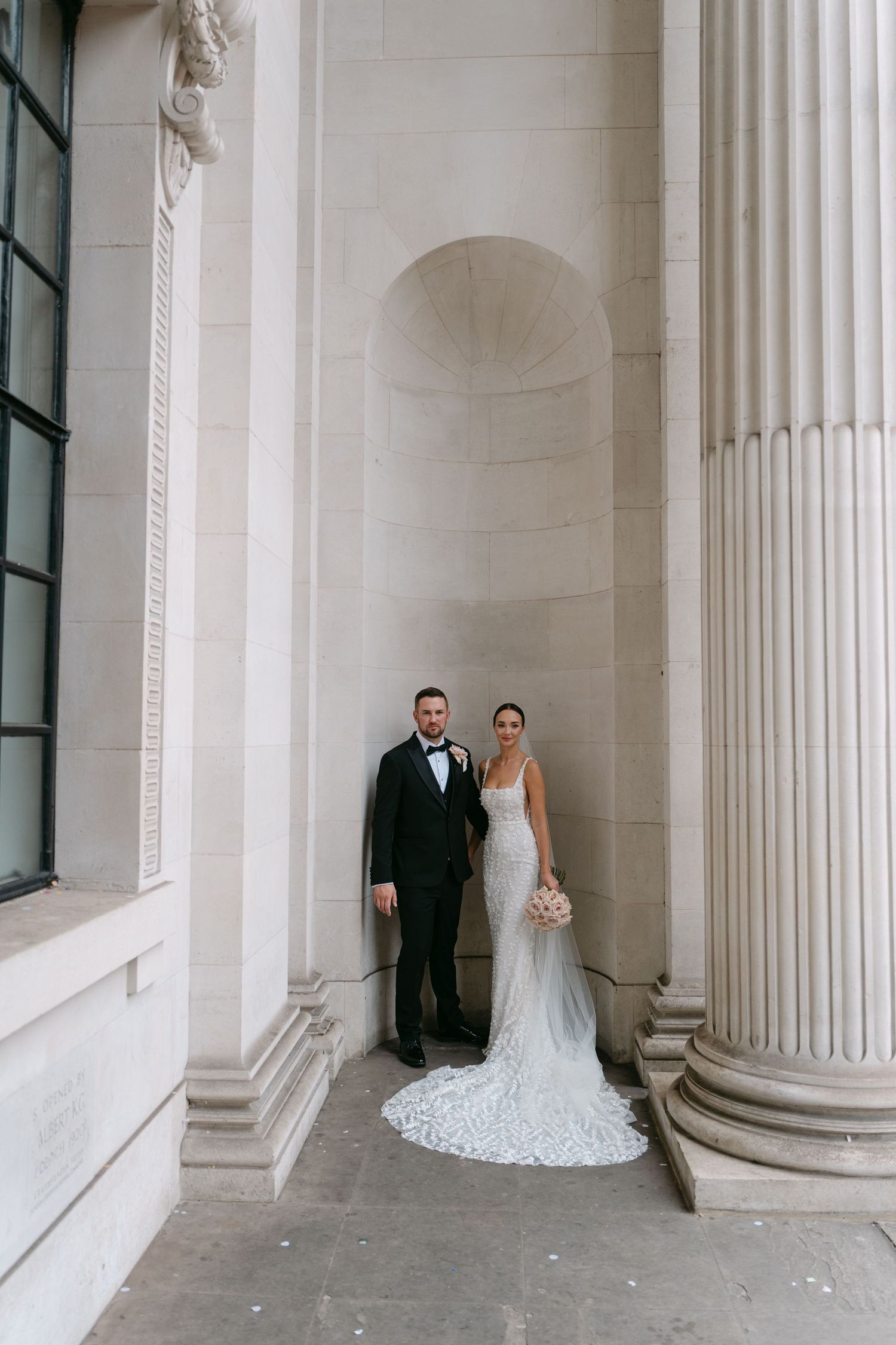 Wedding couple poses for intimate portraits in a classical colonnade setting.
