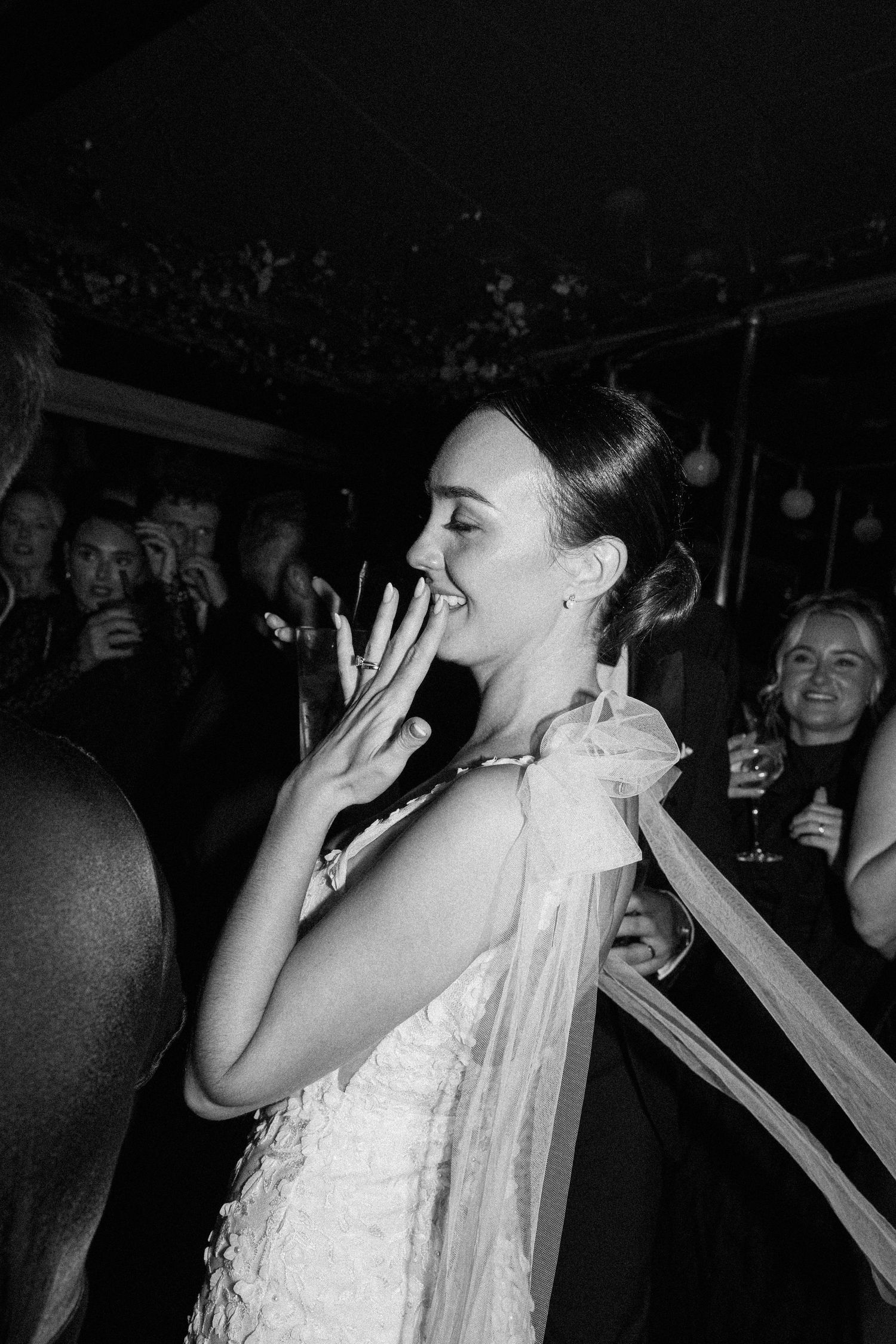 Wedding celebration with dancing and laughter in dark reception venue.