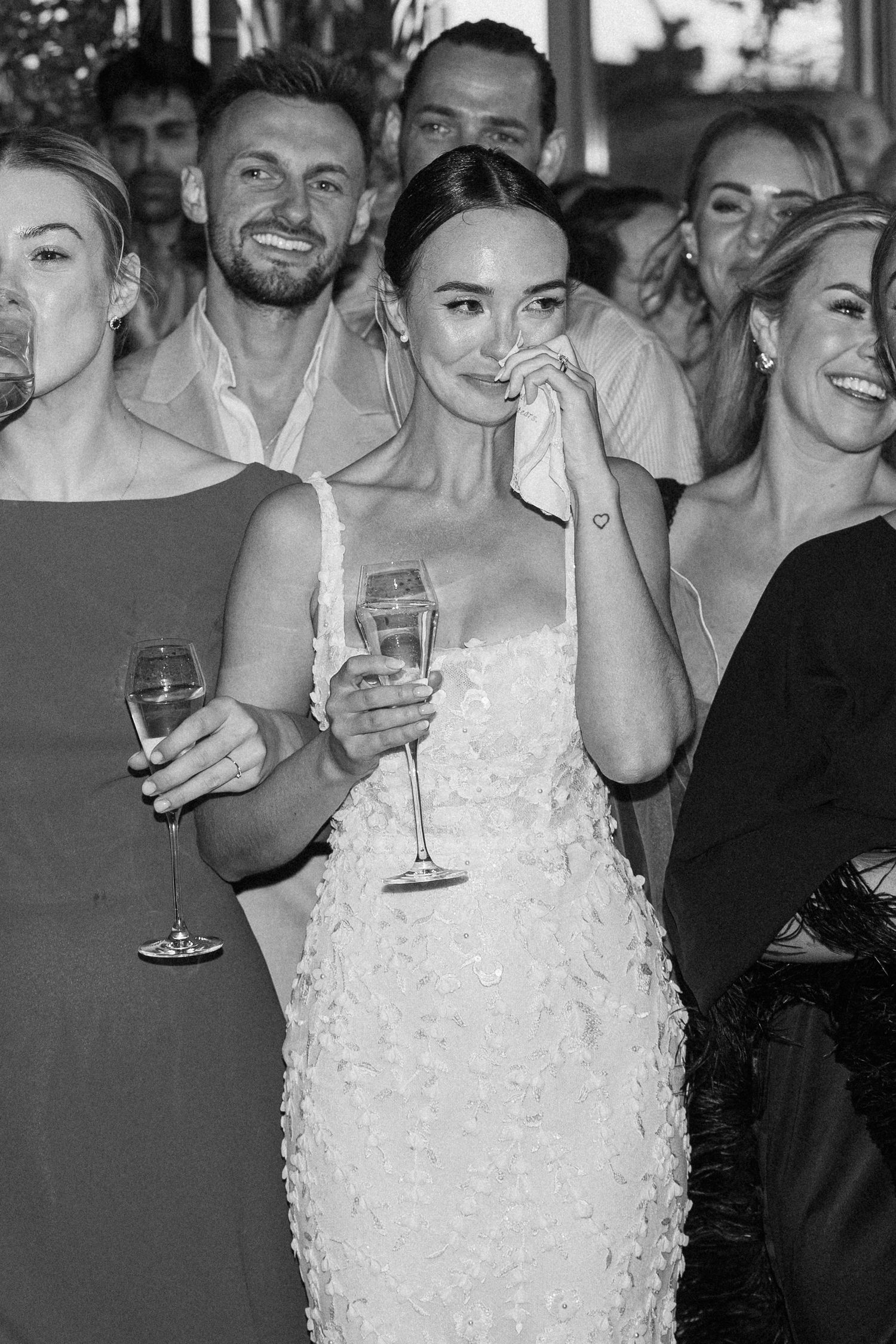 Wedding celebration candid moment captured with guests laughing and holding champagne glasses.