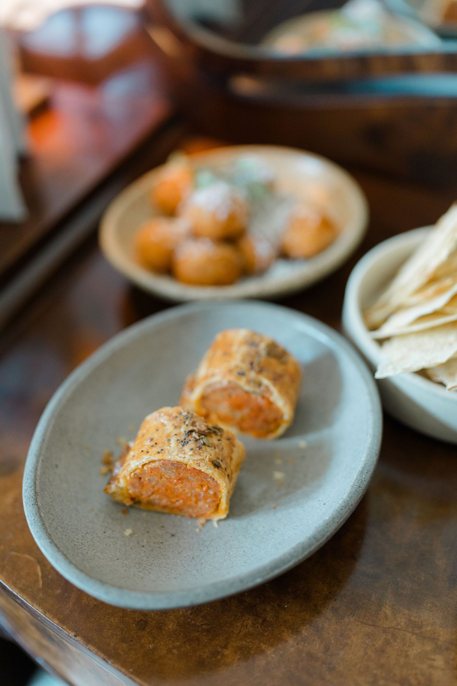 Elegant appetizers on a gray ceramic plate at a wedding reception, featuring rolled pastries with orange filling.