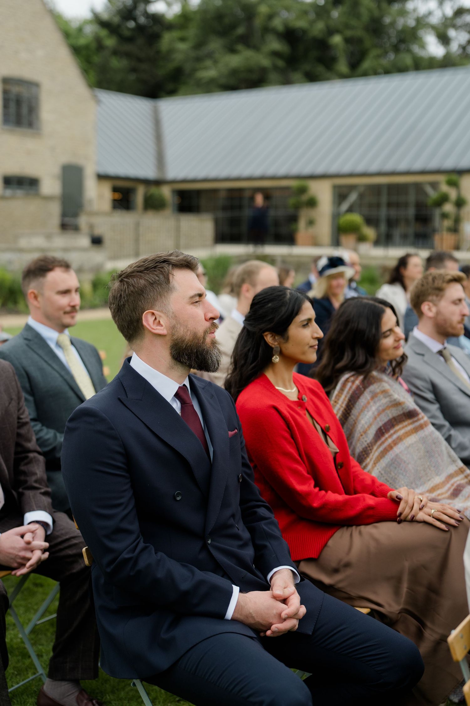 Wedding guests seated outdoors at elegant countryside venue during ceremony.