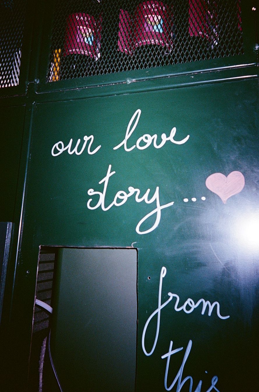 Chalkboard sign reads our love story with a hand-drawn heart at a wedding venue decoration display.
