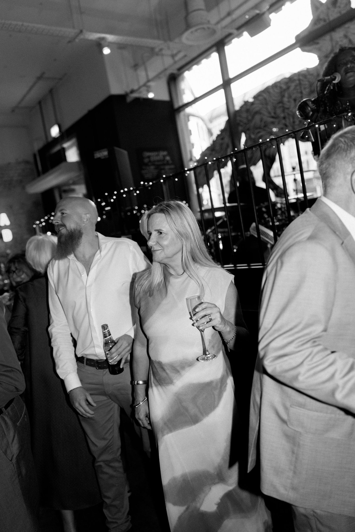 Wedding guests socializing and drinking champagne at evening reception.