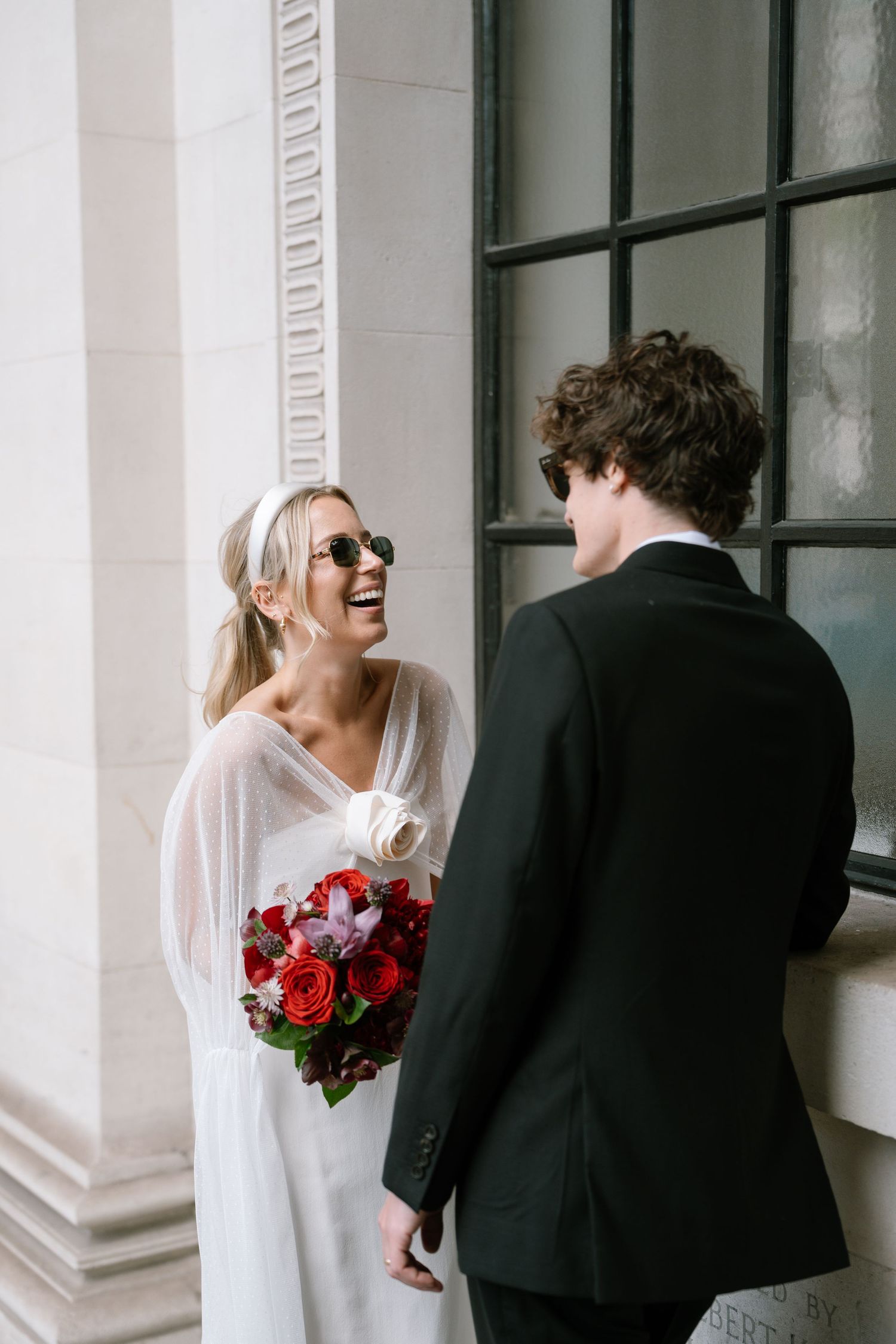 A playful black and white wedding photo series showing a couple posing against a white columned building.