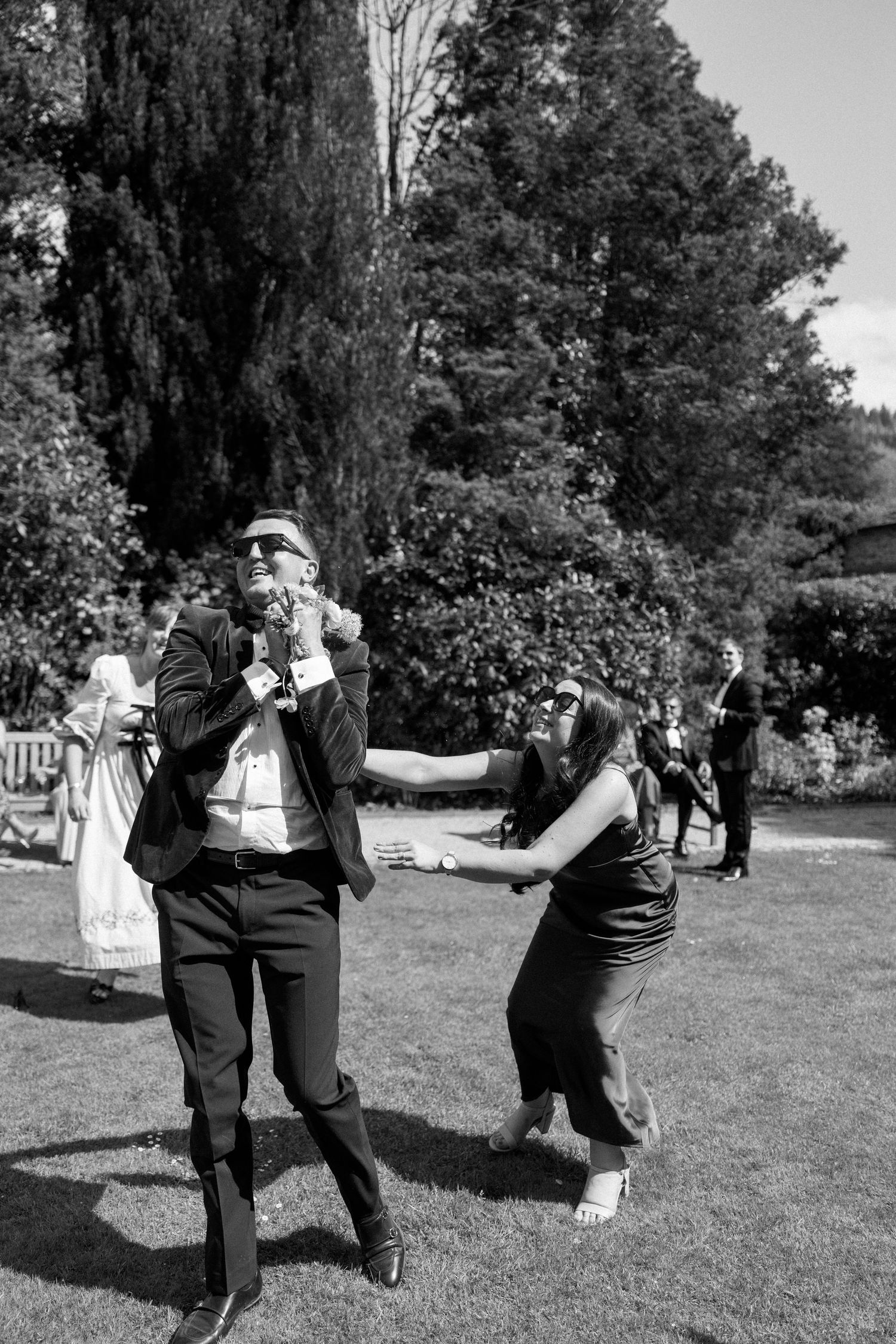 People dance energetically on grass during an outdoor wedding reception.