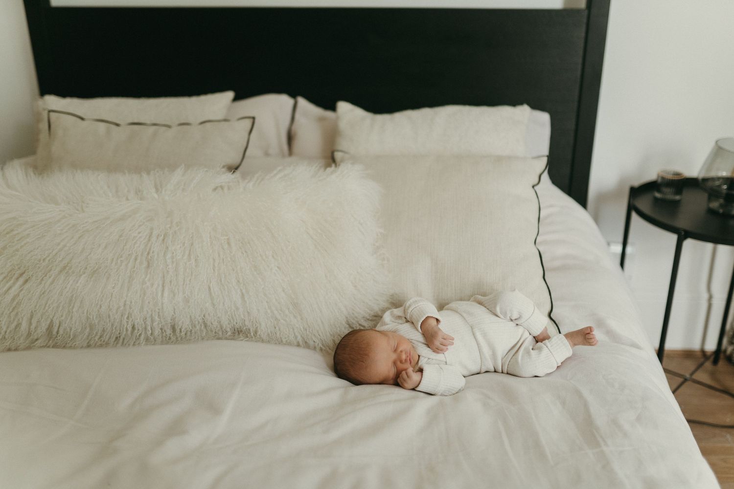 A peaceful sleeping baby on white bedding in natural light.