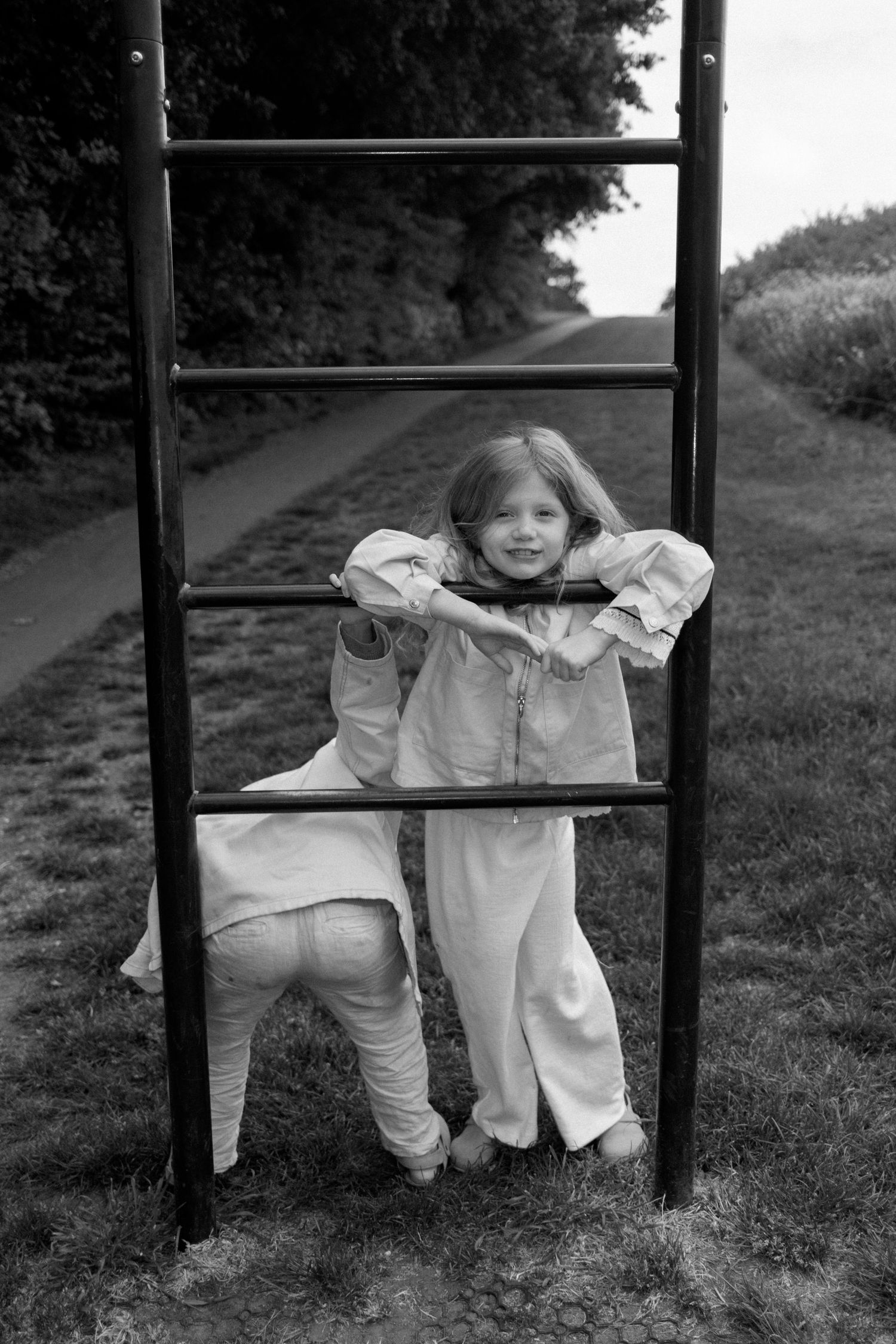 Children playing and posing on outdoor exercise equipment in a park setting.
