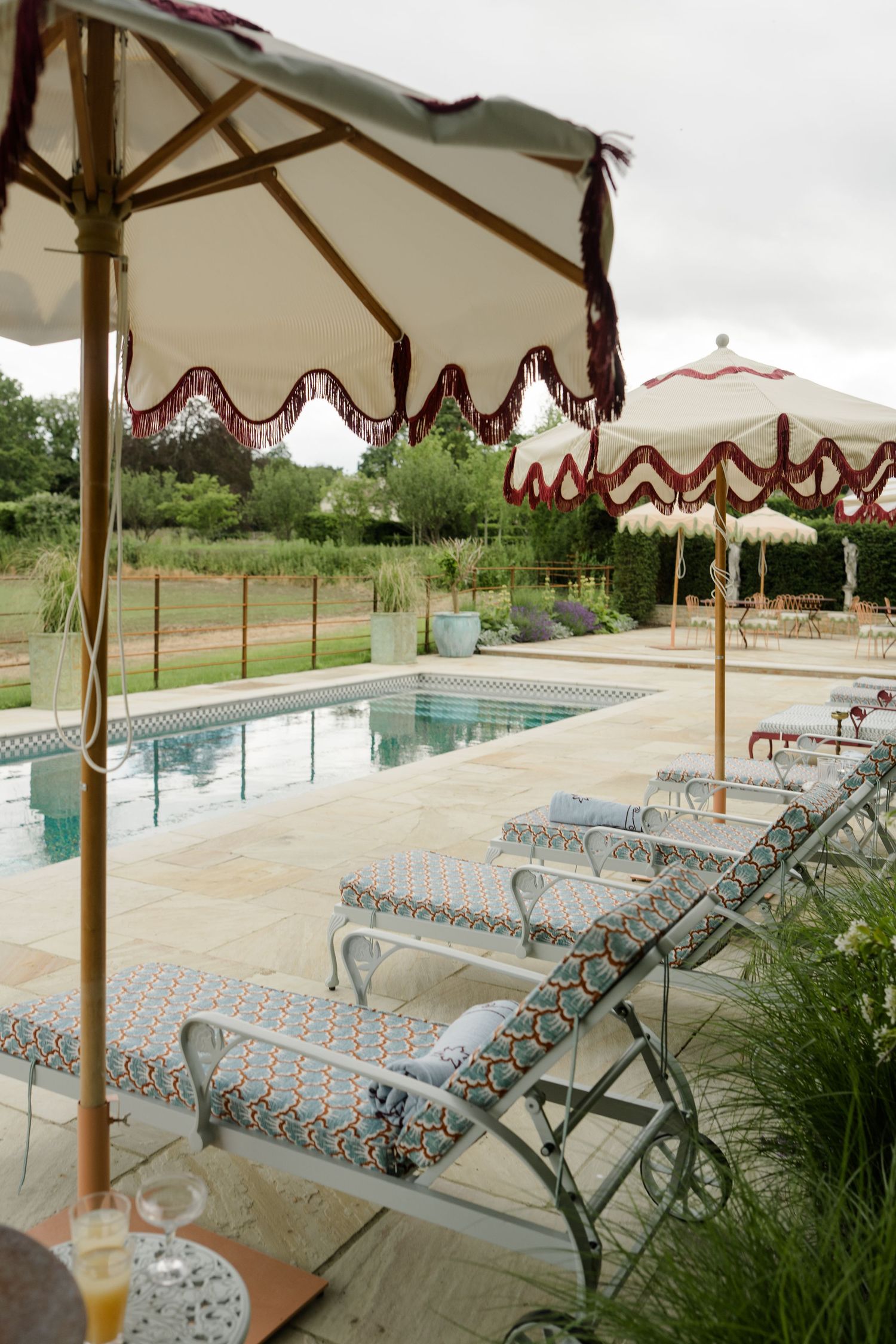 Luxury outdoor pool with patterned loungers and fringed umbrellas at estate.