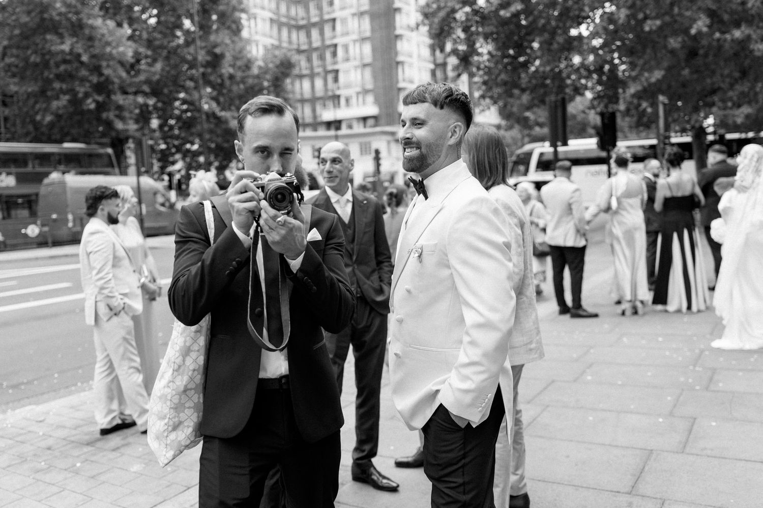 Black and white candid photo of guests mingling outside during an elegant wedding celebration.
