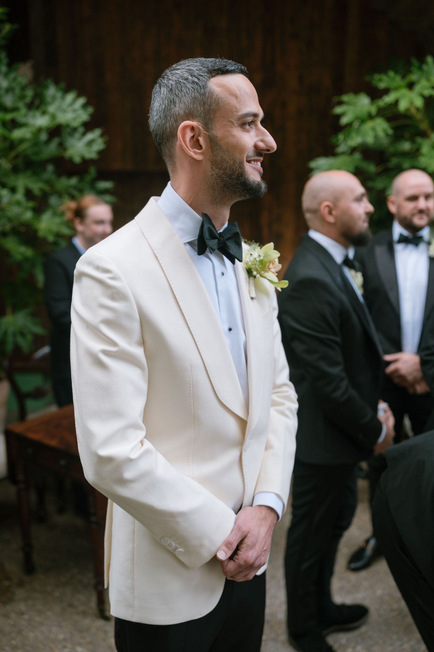 Wedding party members in white dinner jackets and black tuxedos gathered outdoors.