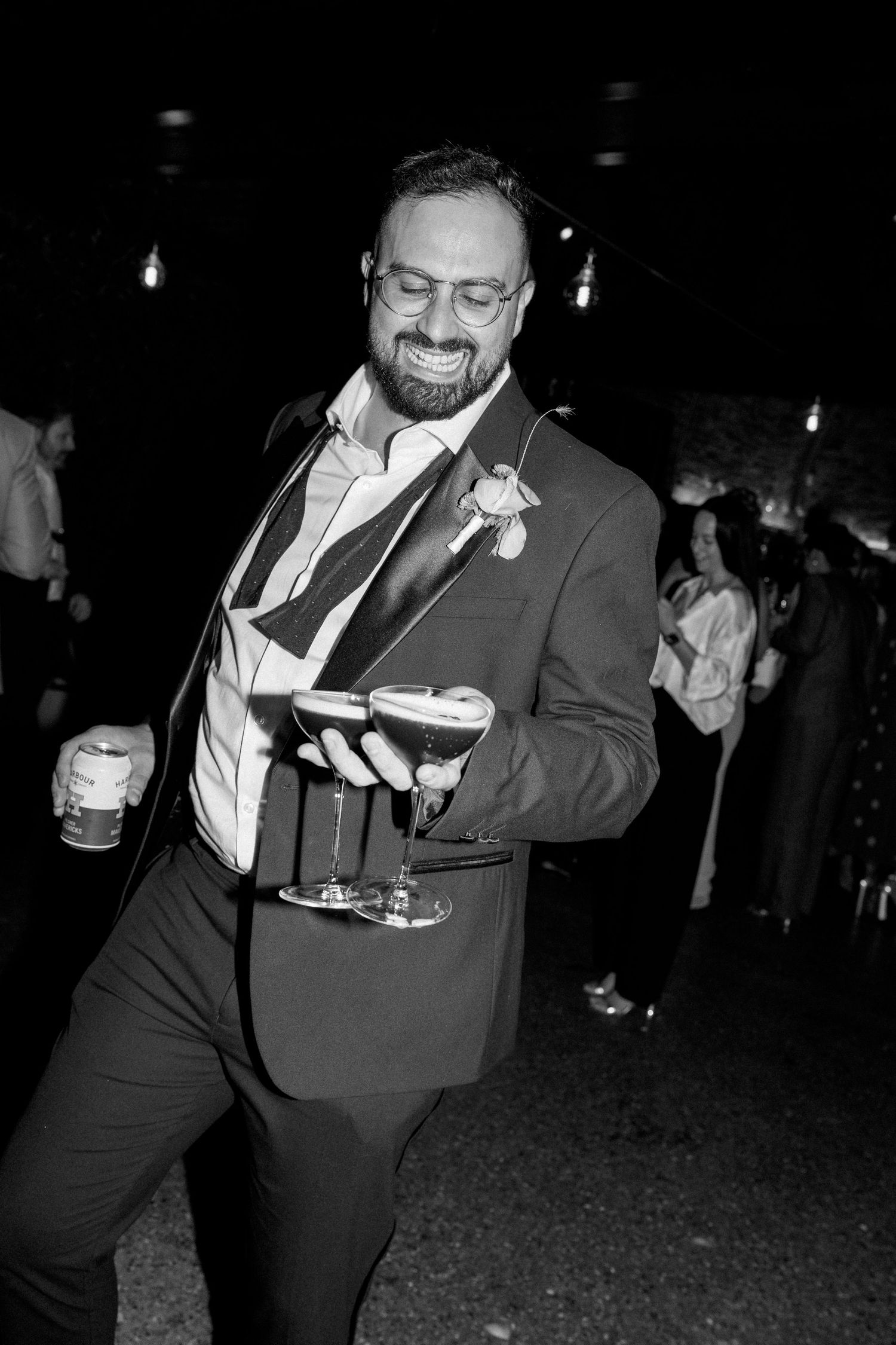 A guest in a dark suit dances joyfully at an indoor celebration.