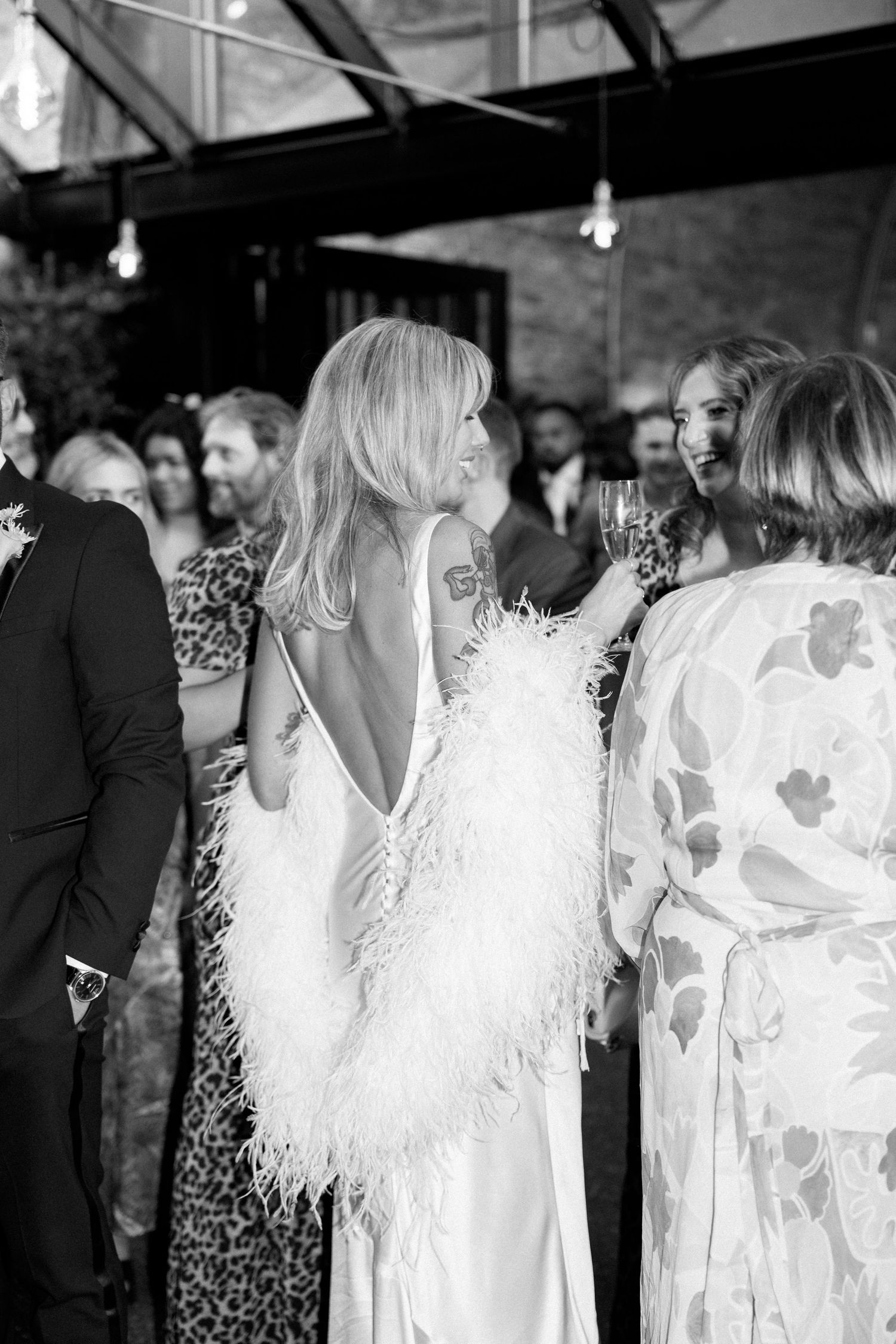 Wedding party in mix of white dresses and animal print attire poses together at reception.