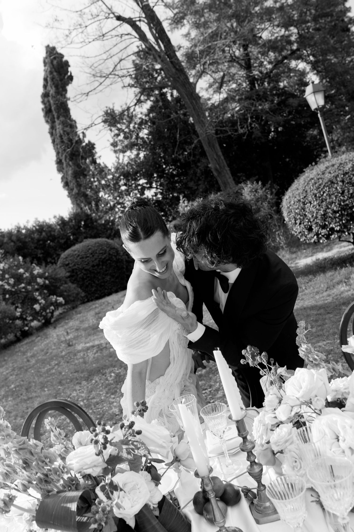 A romantic black and white photo of a couple at their wedding table.