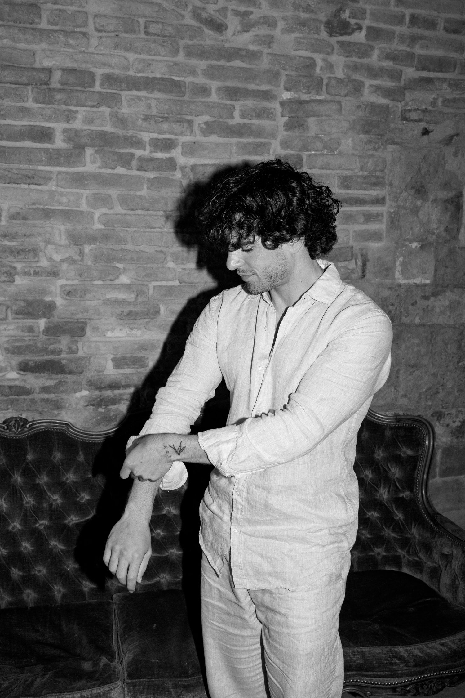 Black and white photos showing a couple in white attire dancing intimately against a brick wall backdrop.