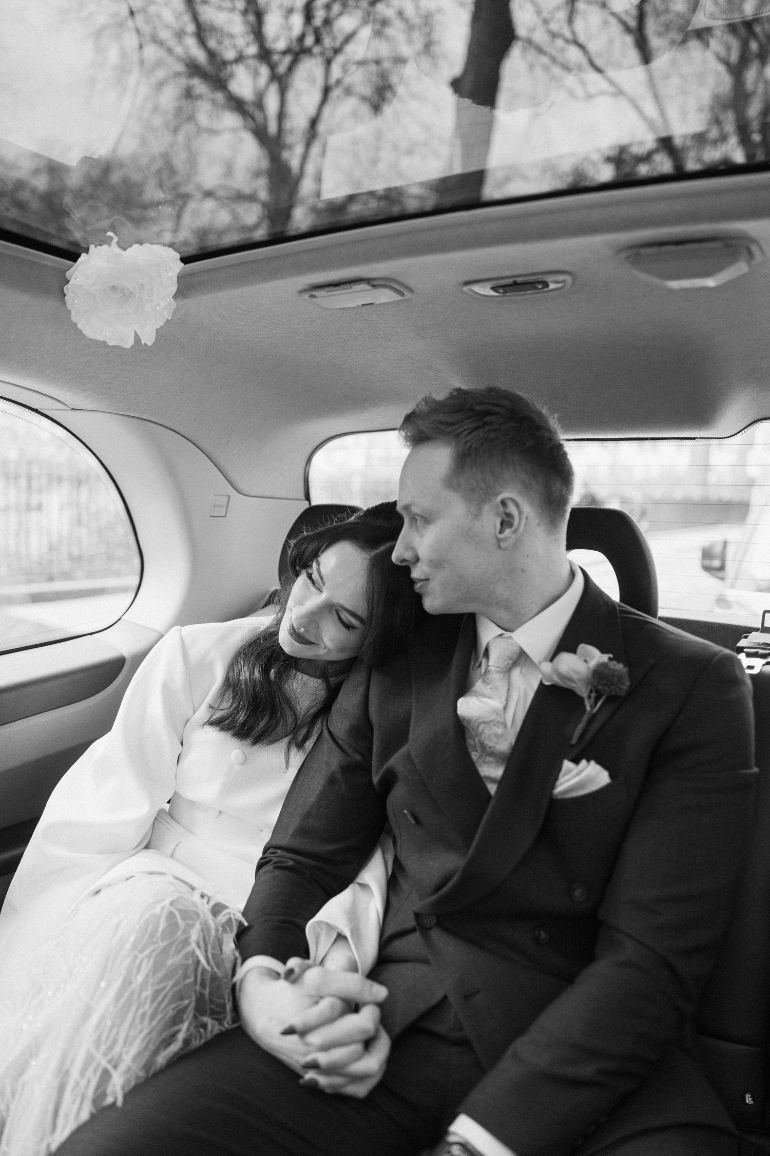 Bride and groom sharing intimate moment in wedding car, black and white romantic portrait.