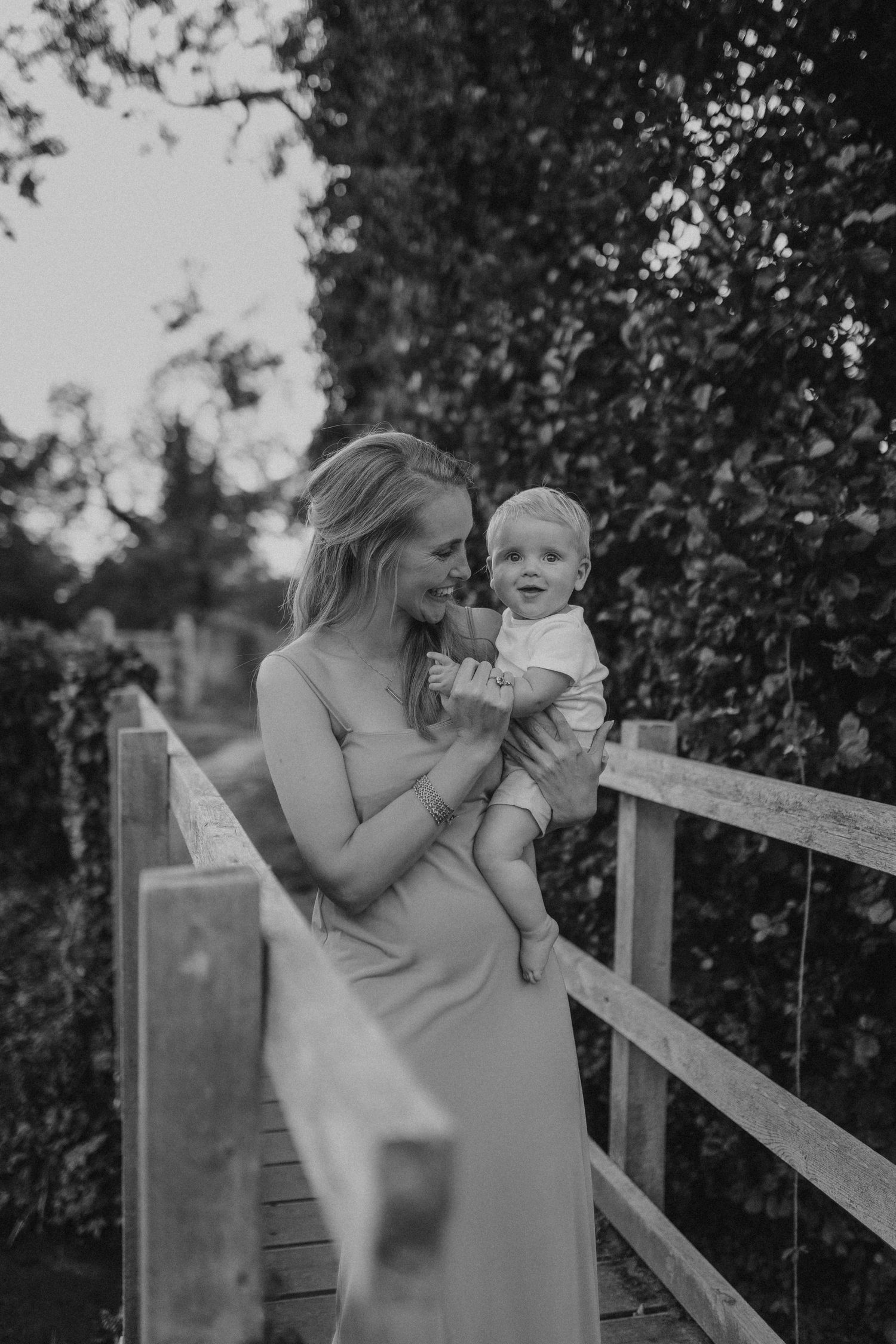 Sweet outdoor family moment captured against rustic wooden fence.
