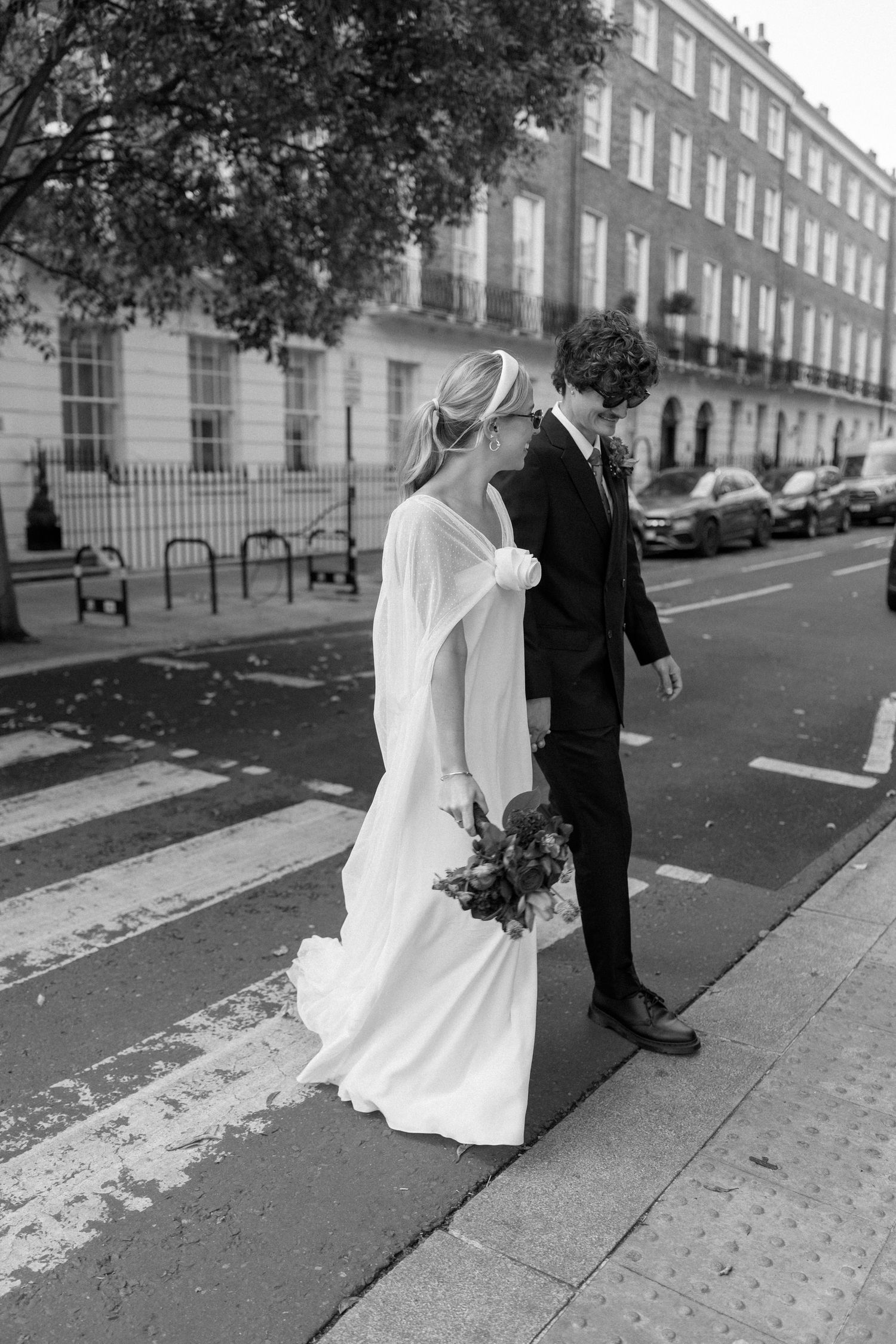 A couple poses on a London sidewalk with classic Georgian townhouses in the background.
