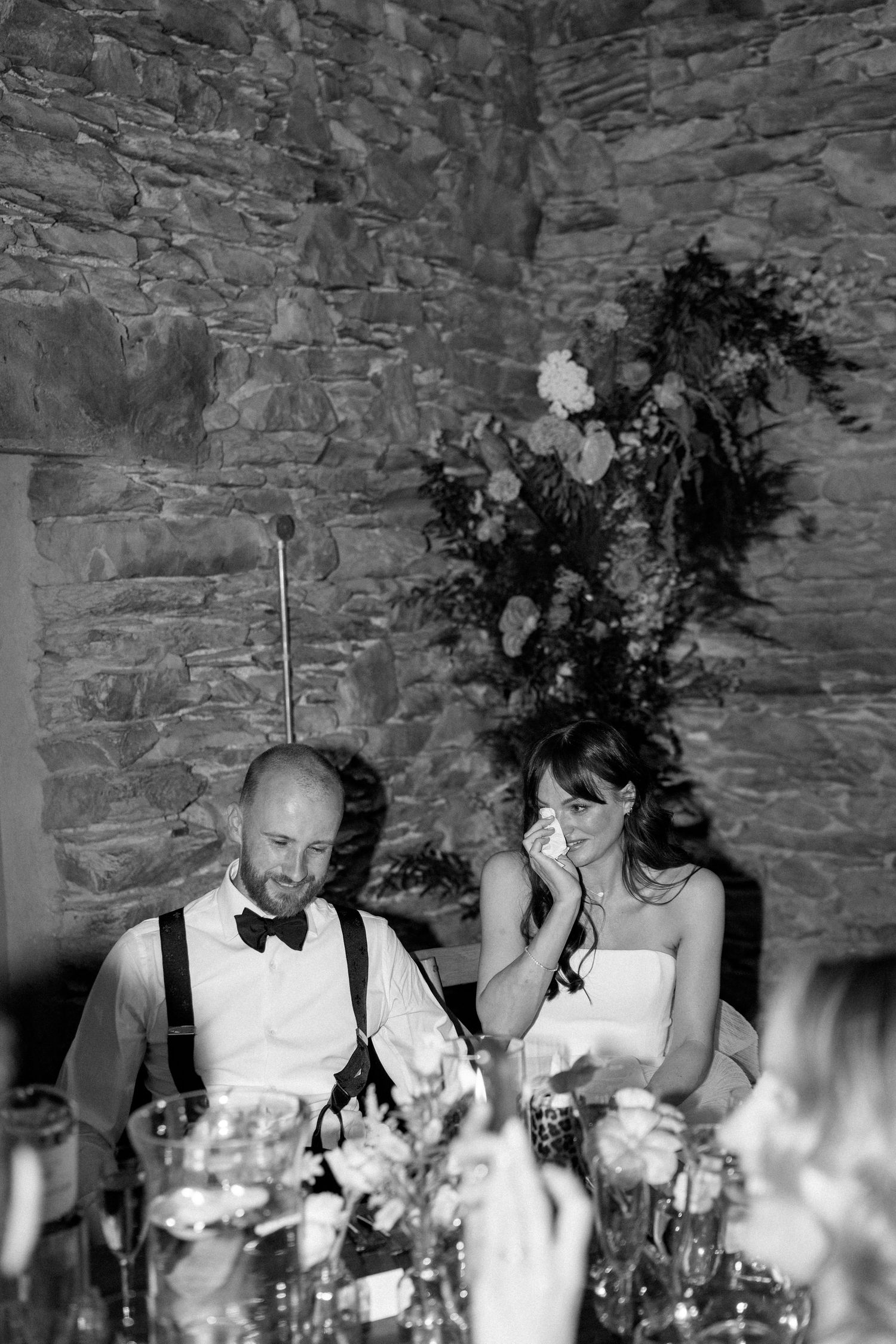 Wedding reception table with floral centerpieces and guests in formal attire.