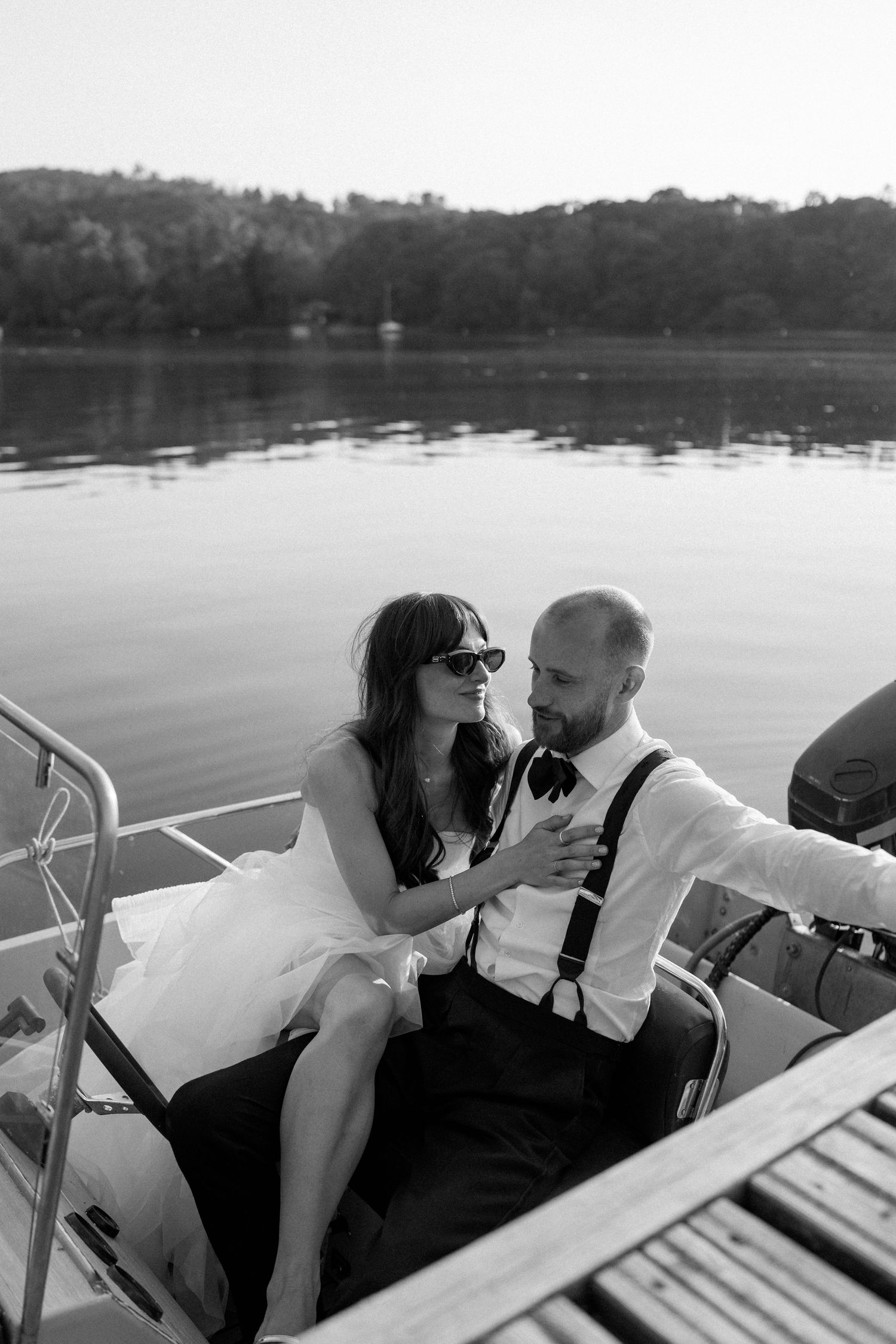 A romantic boat ride on a tranquil lake with a couple sharing an intimate moment at sunset.